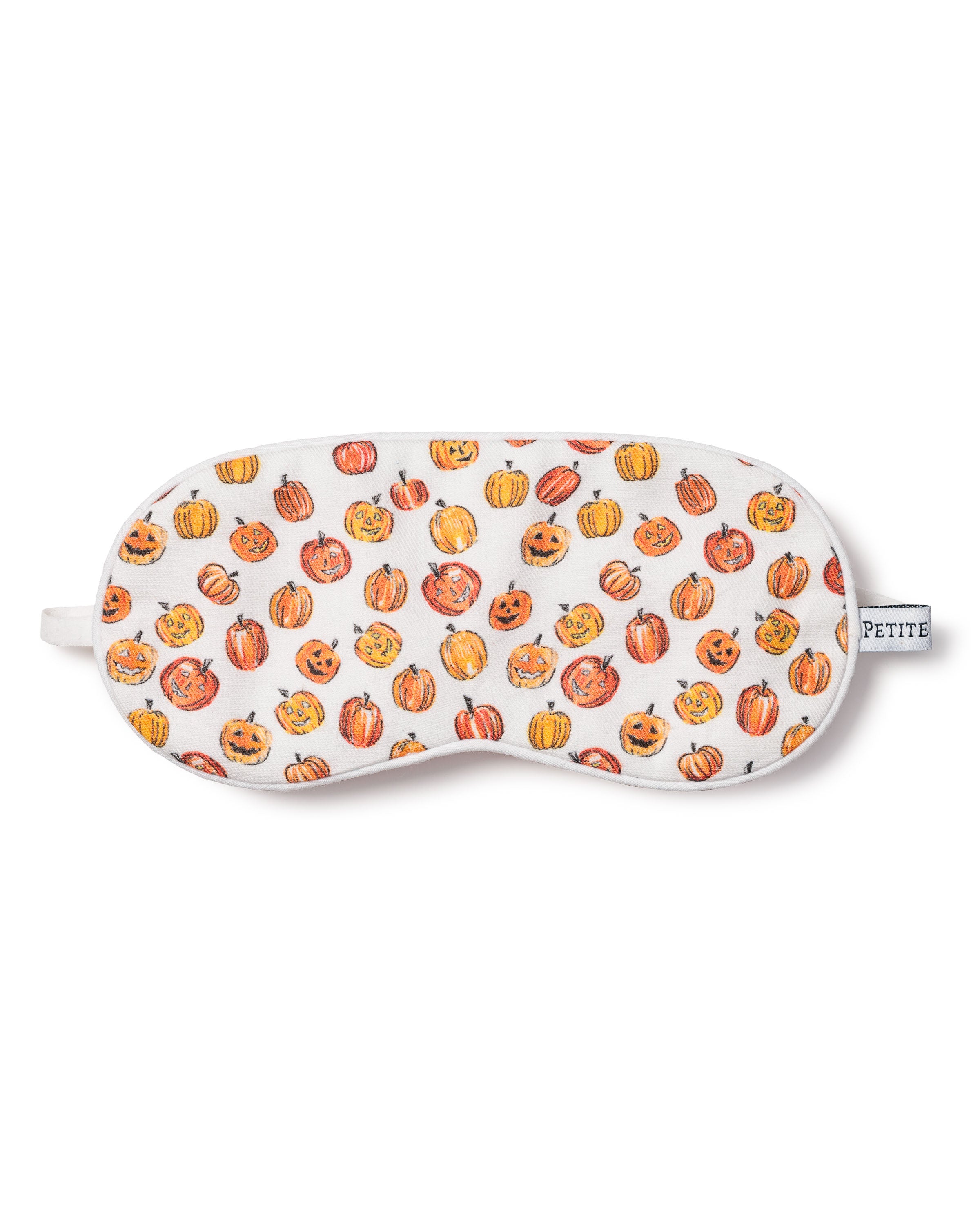 Petite Plumes Kids Twill Sleep Mask in Pumpkin Patch features a festive white design with orange pumpkins and carved faces. A PETITE tab adds charm, making it a delightful Halloween print for matching eye masks.