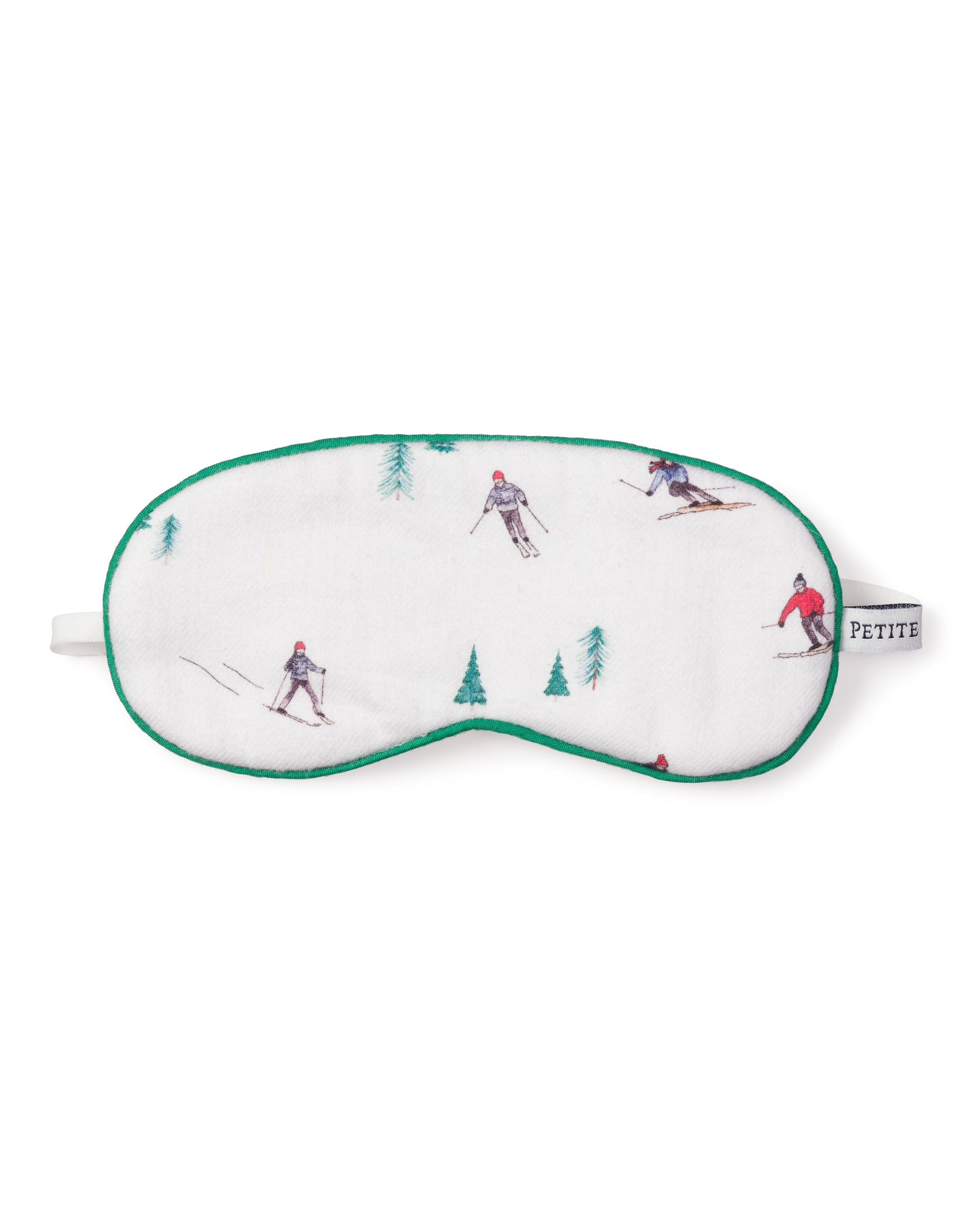 The Kids Flannel Sleep Mask in Après Ski by Petite Plume features a white design with green trim, showcasing small skier and pine tree illustrations. The PETITE label adds a luxurious touch, making it perfect for complementing fine sleepwear.