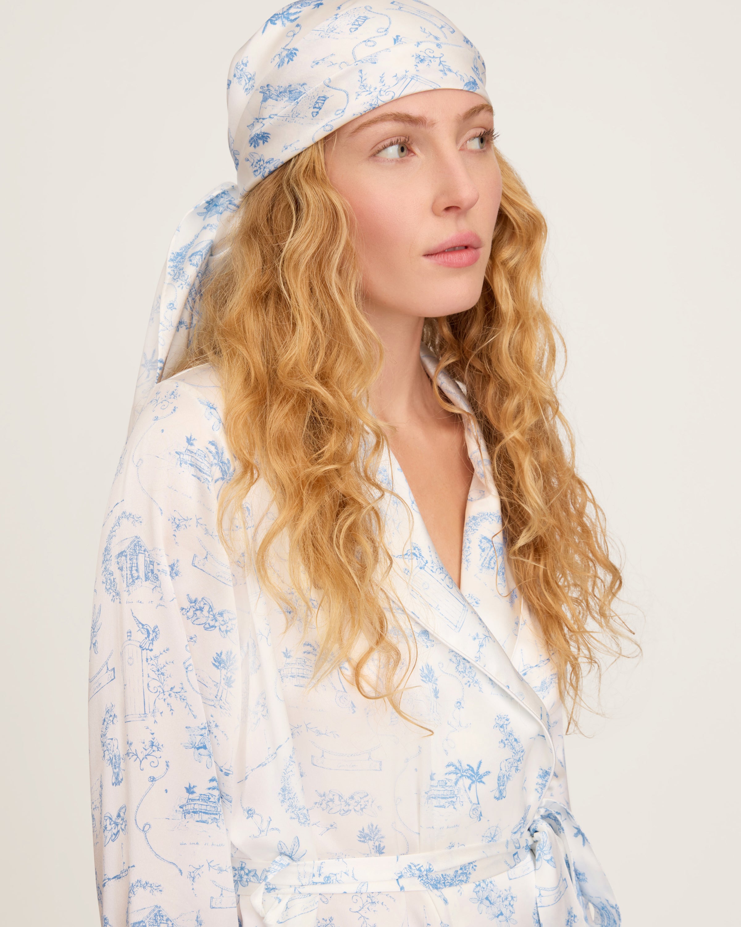 The Petite Plume x Eden Rock Blue Reverie Silk Scarf features delicate blue floral and botanical patterns on white silk, shown loosely folded on a plain white background.