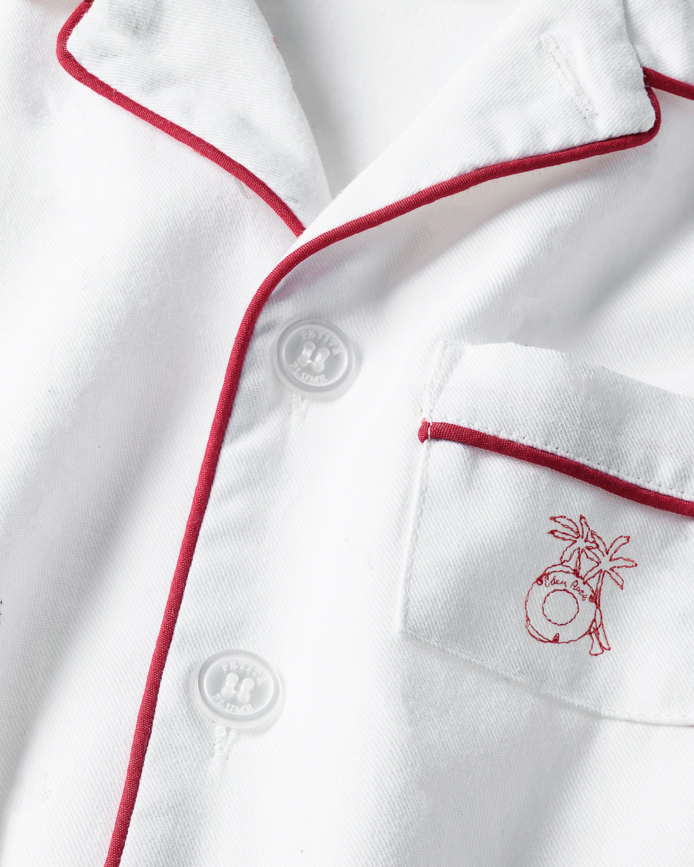 The Petite Plume x Eden Rock St Barth Kids White Twill Short Set includes a white pajama top with red trim and buttons, and features a small embroidered palm tree with coconut design on the chest pocket.
