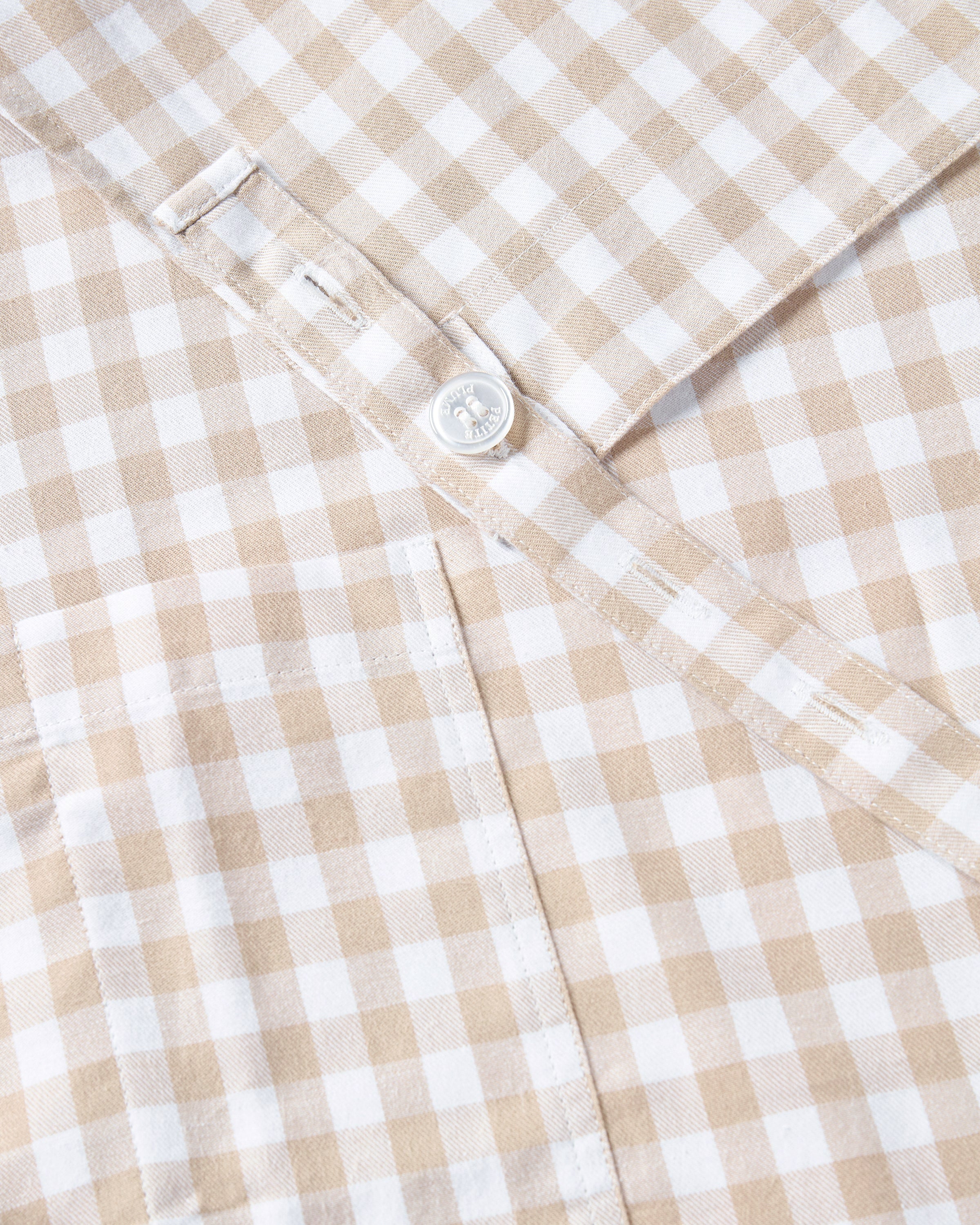 The Adult's Twill Apron in Camel Gingham features a beige and white checkered pattern, a neck loop, front pockets, and waist ties, shown laid flat on a white background.
