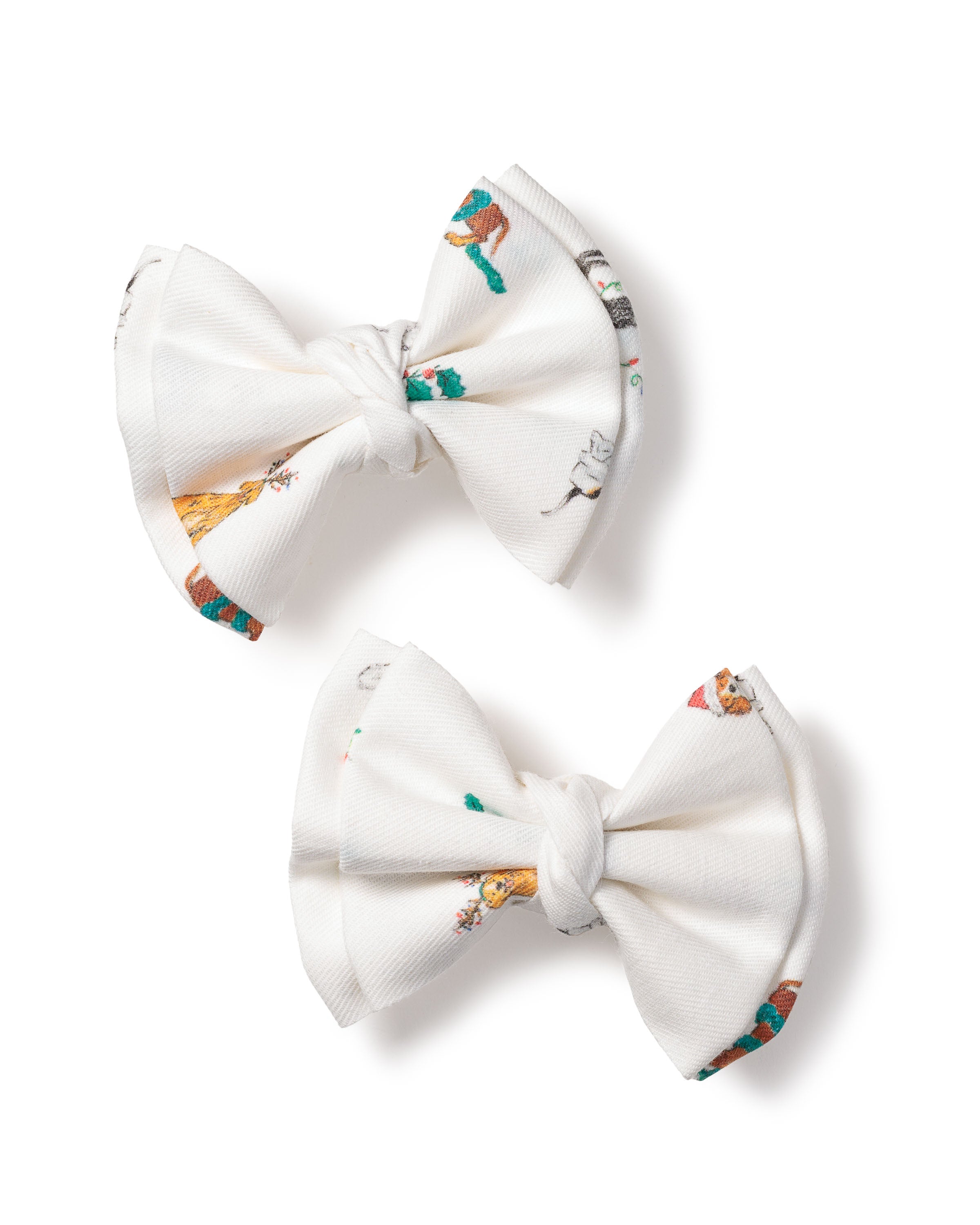 The Girls Twill Hair Bows in Jingle Paws by Petite Plume capture the charm of the Sugar Plum Fairy with two white fabric bows on a plain background featuring subtle multicolored illustrations, each bow showcasing whimsical variations akin to dancers in a Nutcracker ballet.