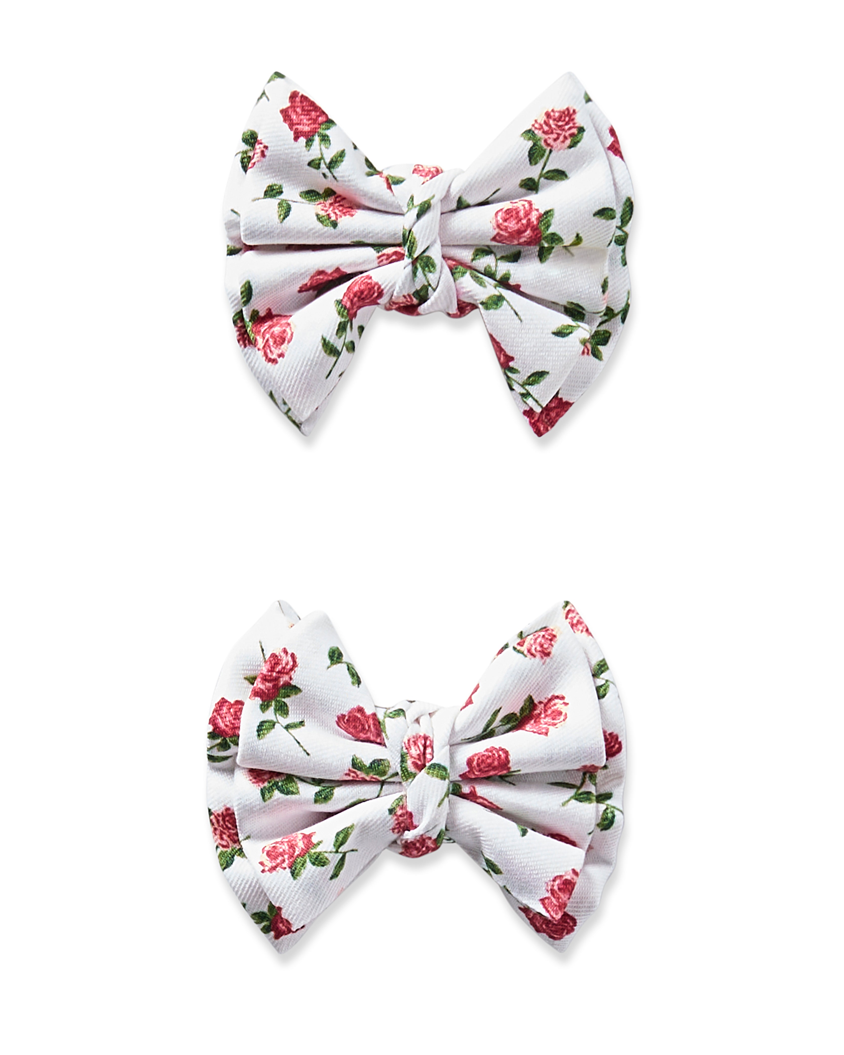 Two white hair bows from Petite Plumes Girls Twill collection, adorned with pink roses and green leaves, feature gathered fabric knotted in the center. Displayed vertically on a white background, they are perfect for pairing with pajamas or dressy outfits.