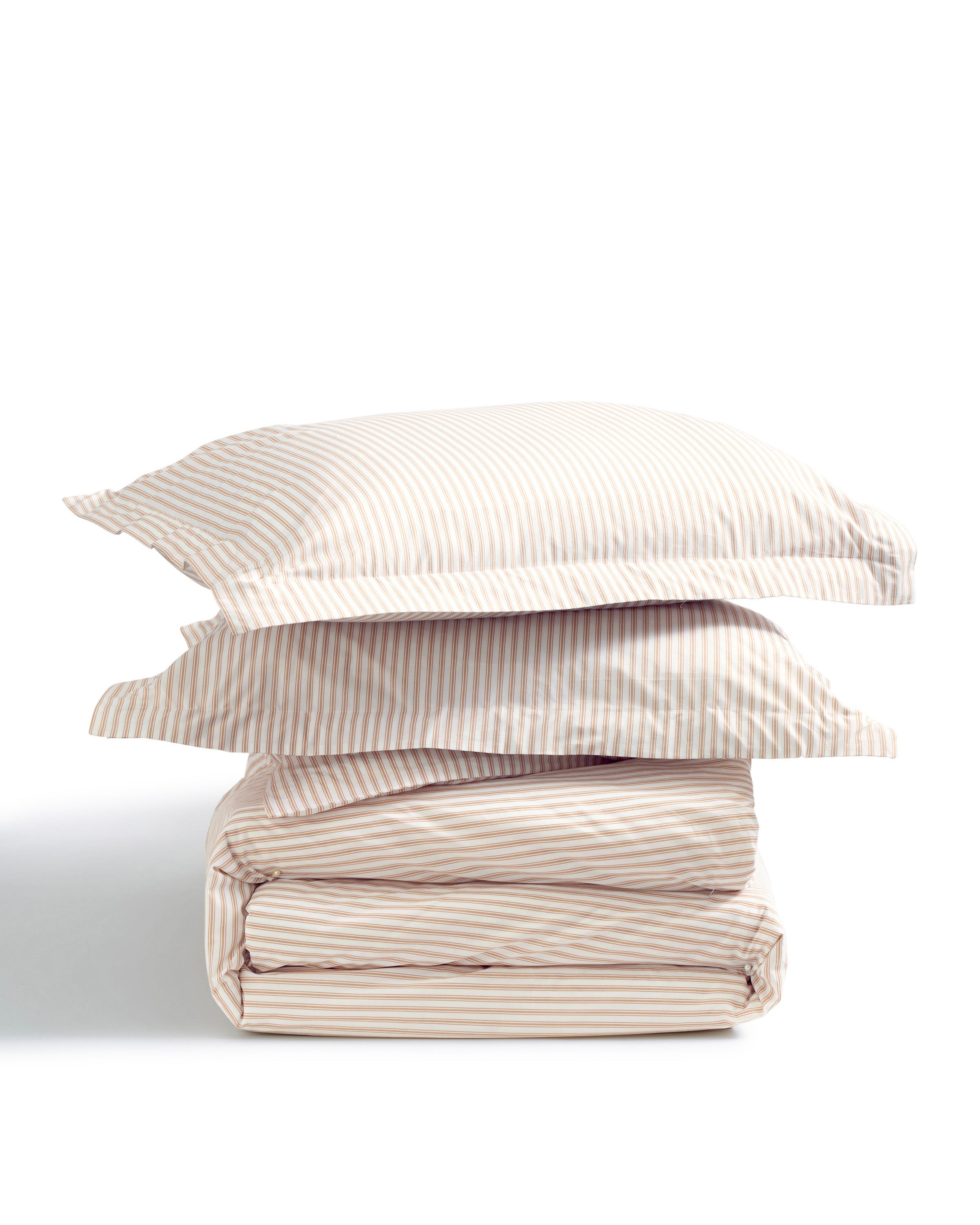 Two Luxe Premium Percale Duvet Set pillowcases in Camel Ticking Stripe are stacked on top of a folded matching sheet set, all arranged against a white background.