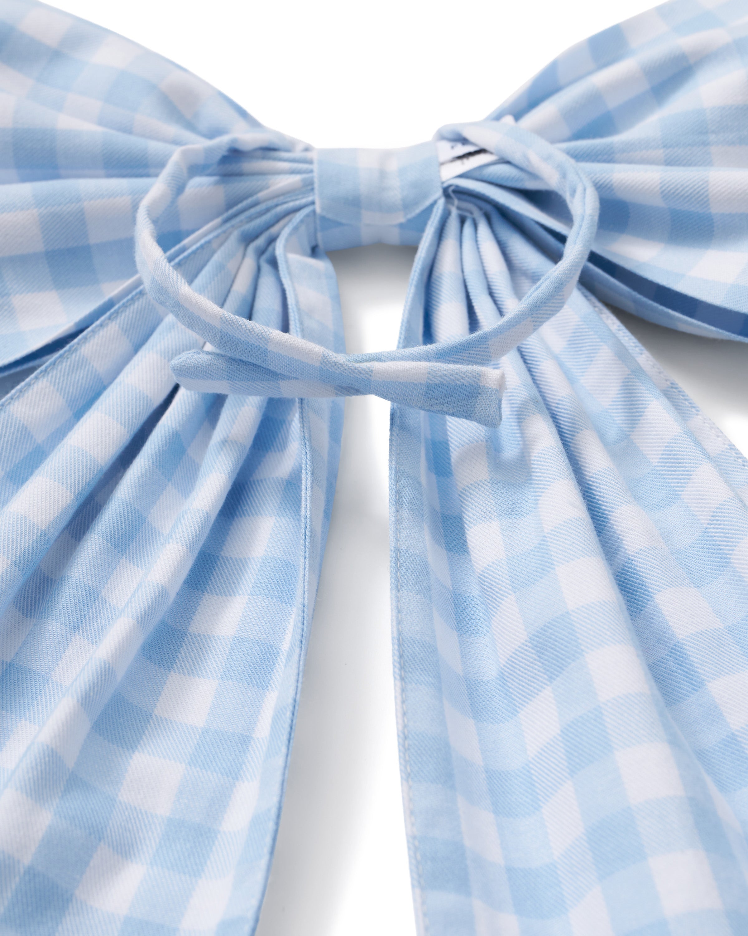 A floral wreath of small white and pink blooms hangs on a beige door, adorned with the Easter Basket and Wreath Bow in Light Blue Gingham featuring long ribbon tails.