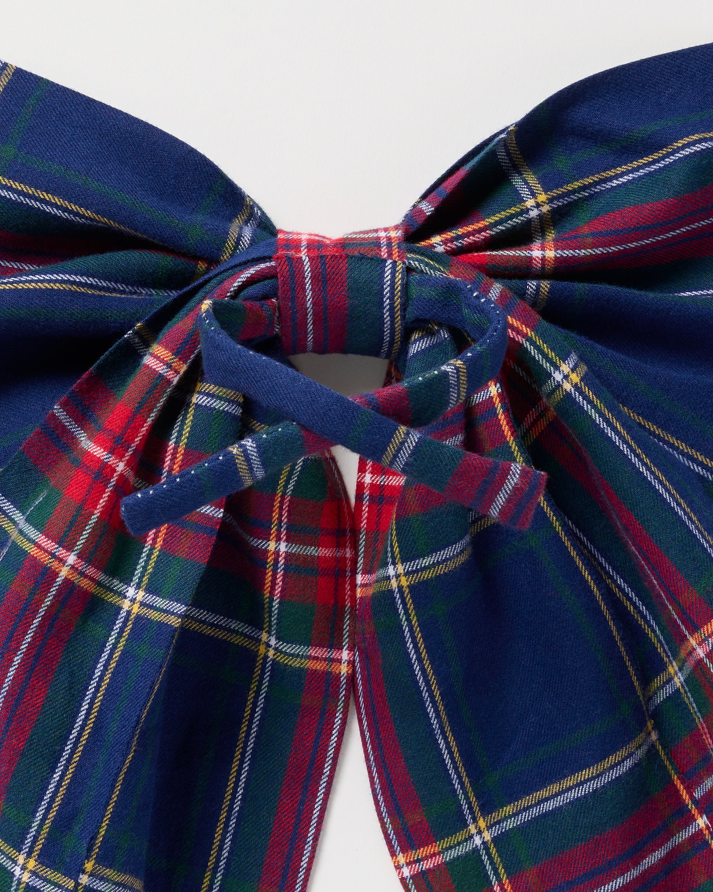 A close-up of the Petite Plume Wreath Bow in Windsor Tartan showcases a neatly tied bow featuring a festive blue, red, and green plaid with white and yellow hints, set against a plain white background.