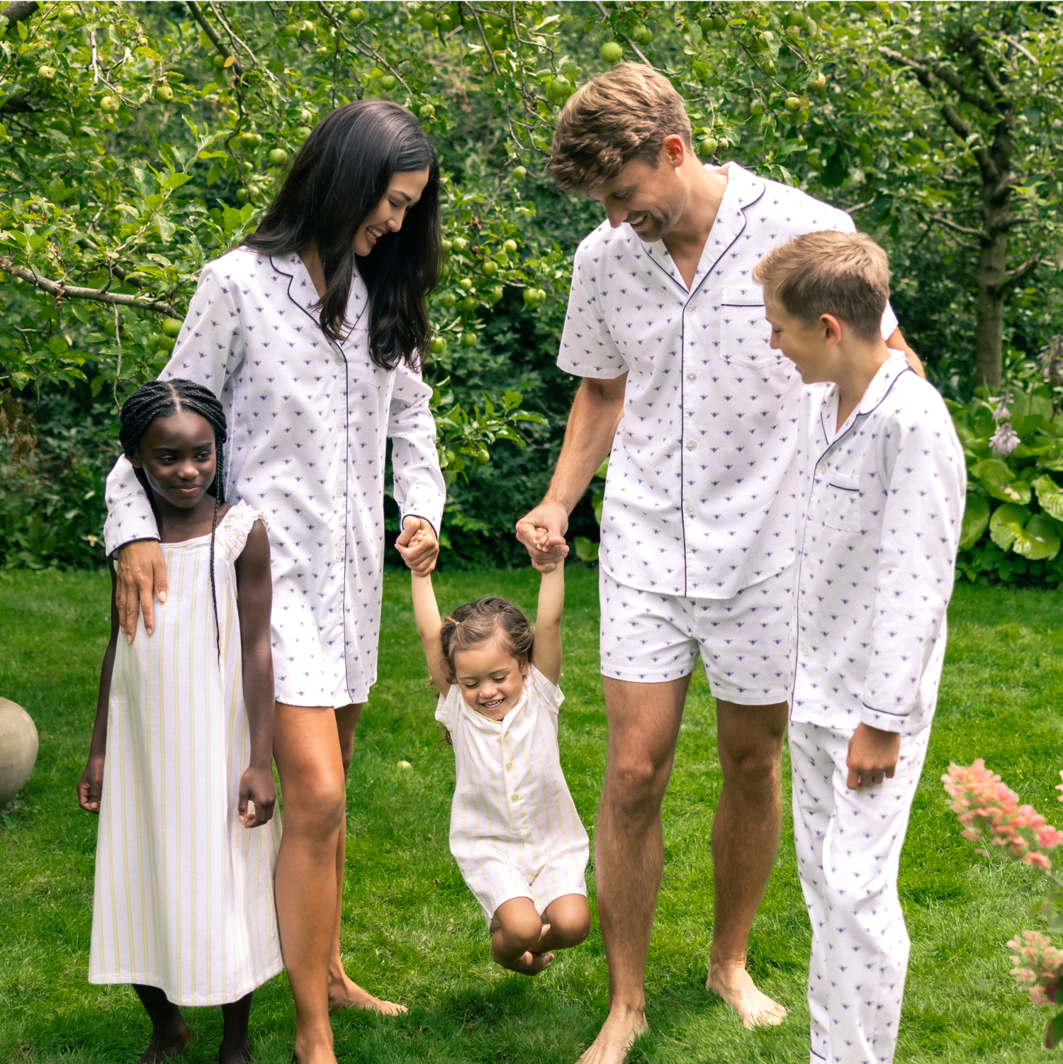 Group of people outside in a garden playing wearing yellow and navy pajamas