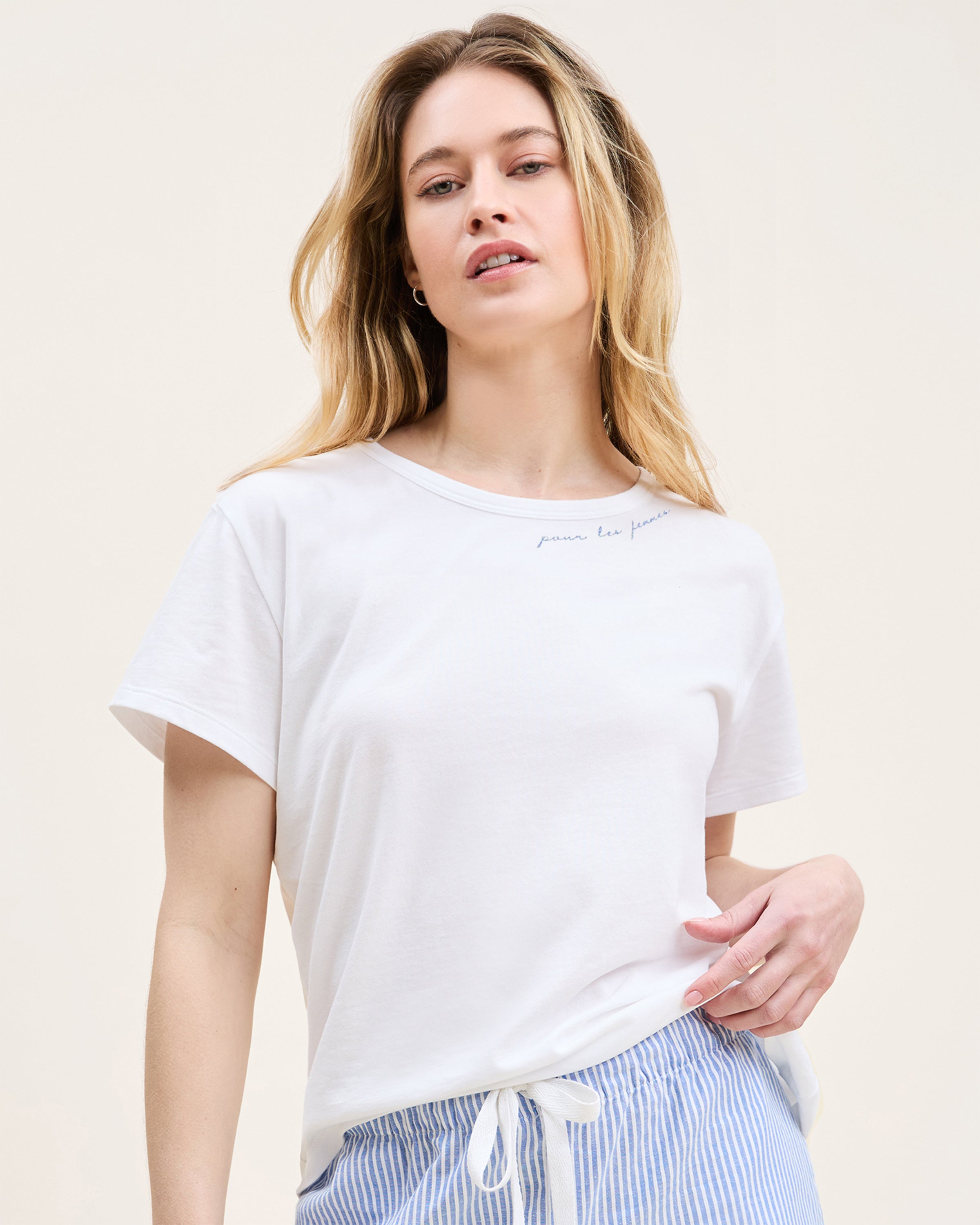 Close-up of a woman wearing the Women's Pima Essential Crew Neck Tee with "Pour Les Femmes" embroidered in blue cursive near the collar. Only her lower face, neck, and upper chest are shown.