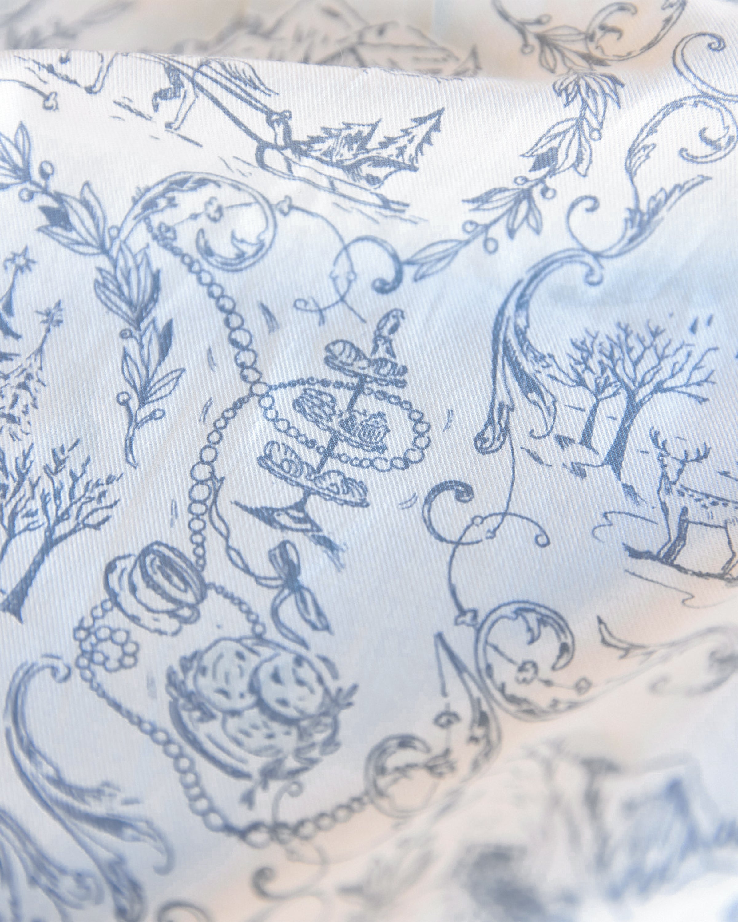 The Maman x Petite Plume Alpine Toile Tea Towels by Petite Plume showcase a delicate slate blue pattern with intricate florals, leaves, and charming details like an anchor, pearls, and trees. This limited-edition design evokes vintage toile patterns, ideal for a festive tablescape.