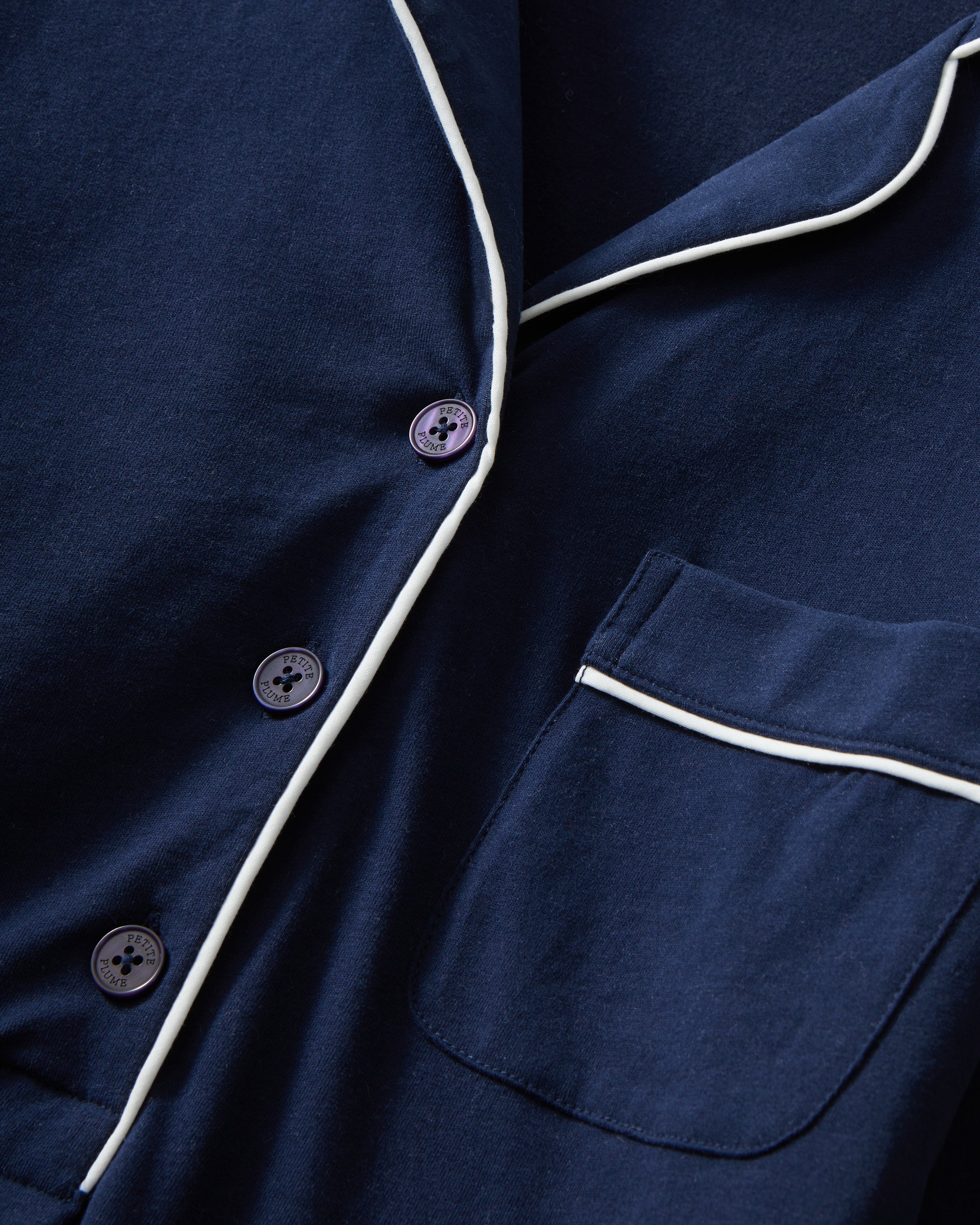 The Women's Pima Maternity Nightshirt in Navy features long sleeves, white piping on the collar, pocket, and cuffs, a chest pocket, button v-neckline, and a relaxed fit.