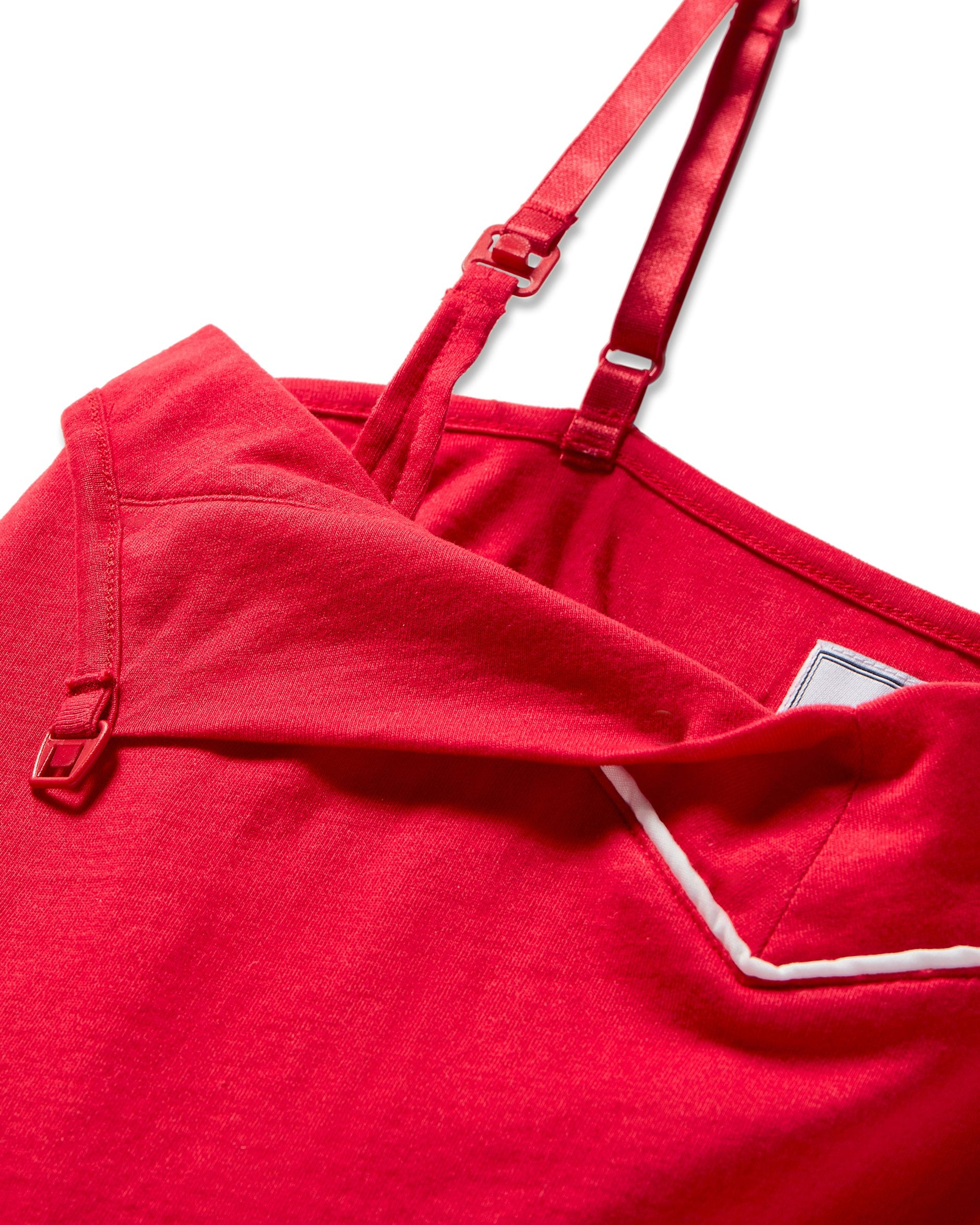 Close-up of Petite Plumes Womens Pima Maternity Camisole in Red featuring adjustable straps and a fold-over neckline. Tailored for nursing mothers, the soft fabric has white piping that accents the intricate details and texture, offering comfort throughout pregnancy.