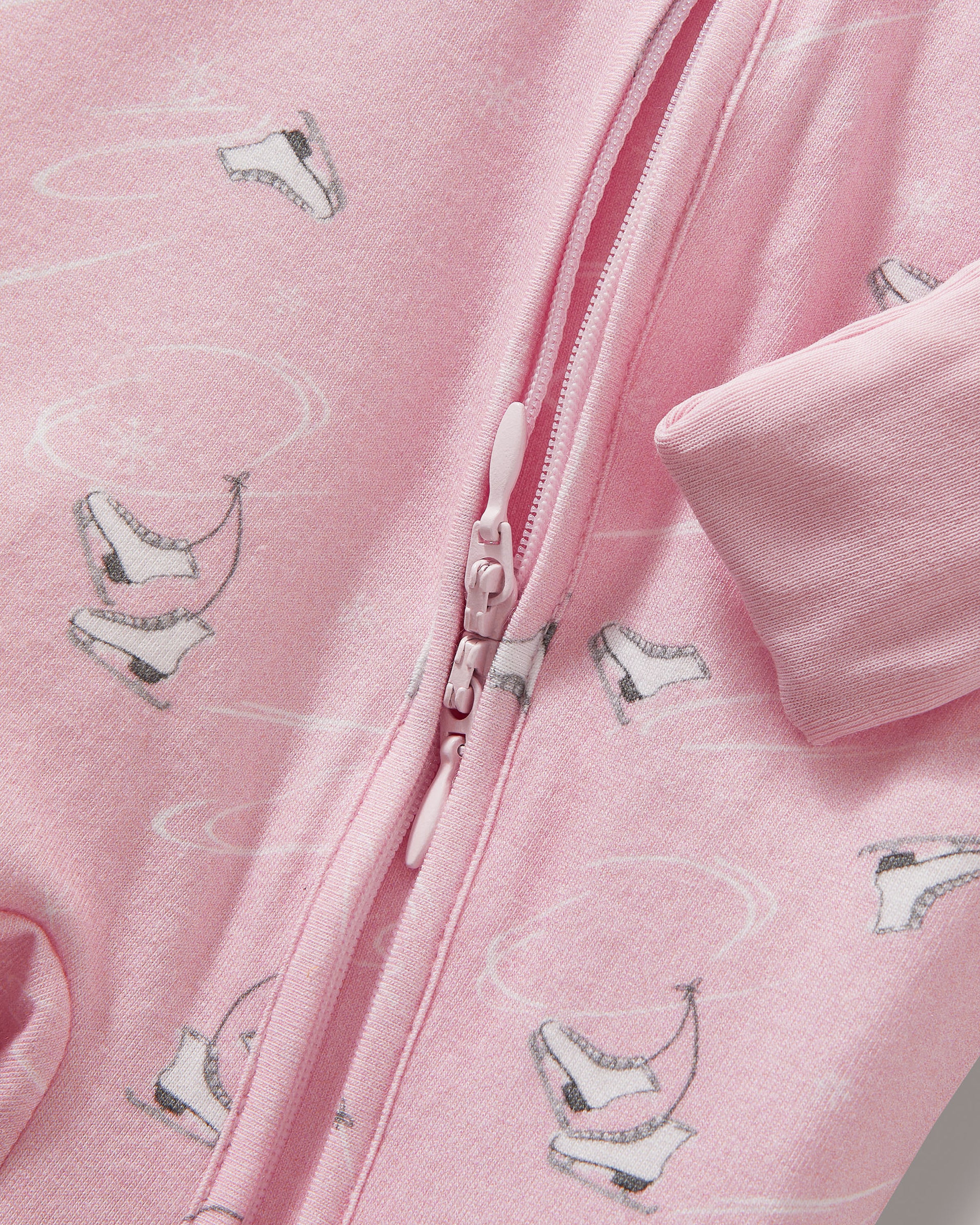 The Baby's Pima Peekaboo Romper in Winter Skates is a pink long-sleeve, long-leg romper with a subtle white bird print, diagonal neck-to-leg zipper, and ribbed cuffs at wrists and ankles.