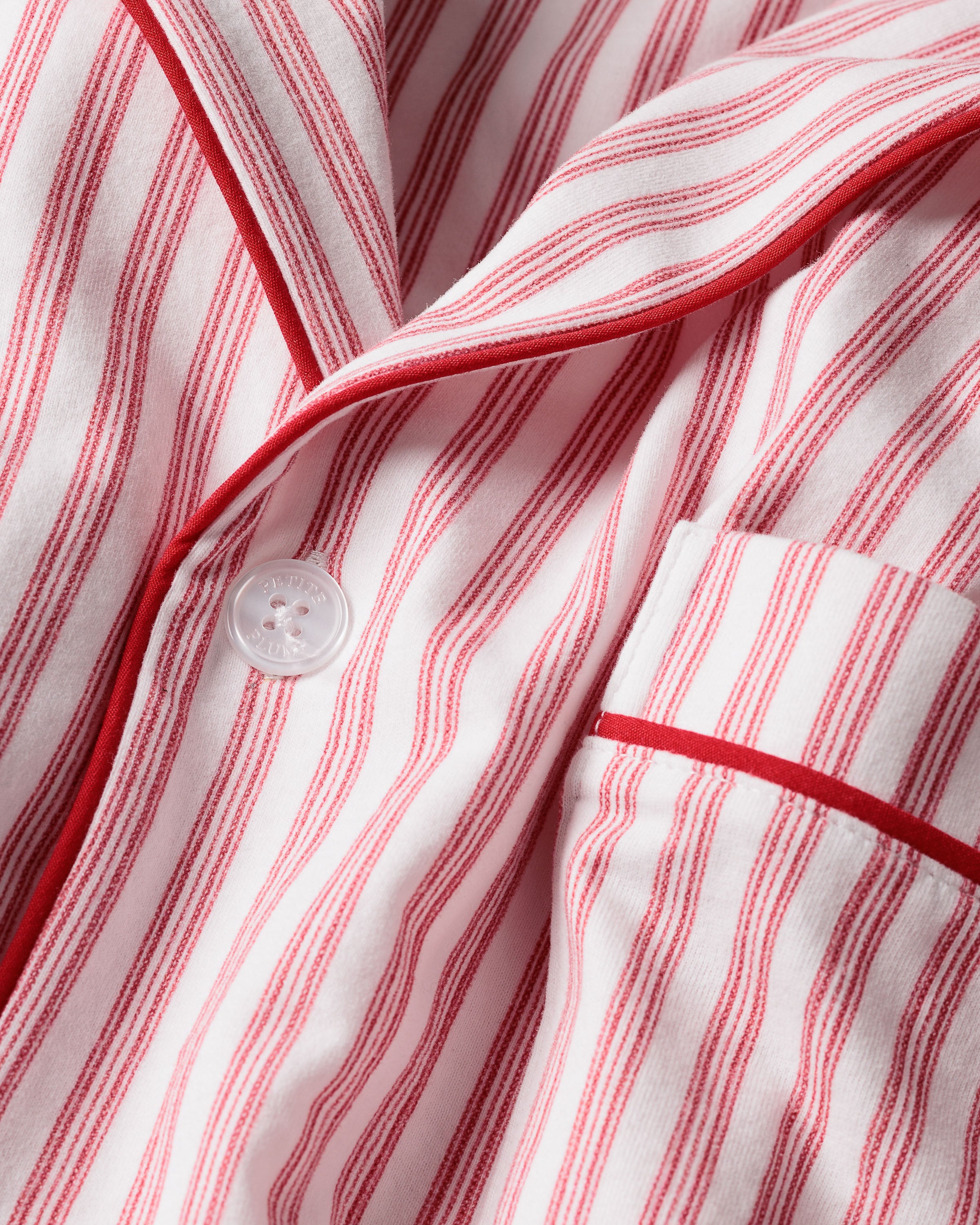 This close-up features the Mens Pima Pajama Top by Petite Plume in Antique Red Ticking. The luxurious yarn-dyed Peruvian Pima cotton showcases vertical red and white stripes with a visible button and pocket outlined in red piping, ensuring softness and comfort for restful nights.