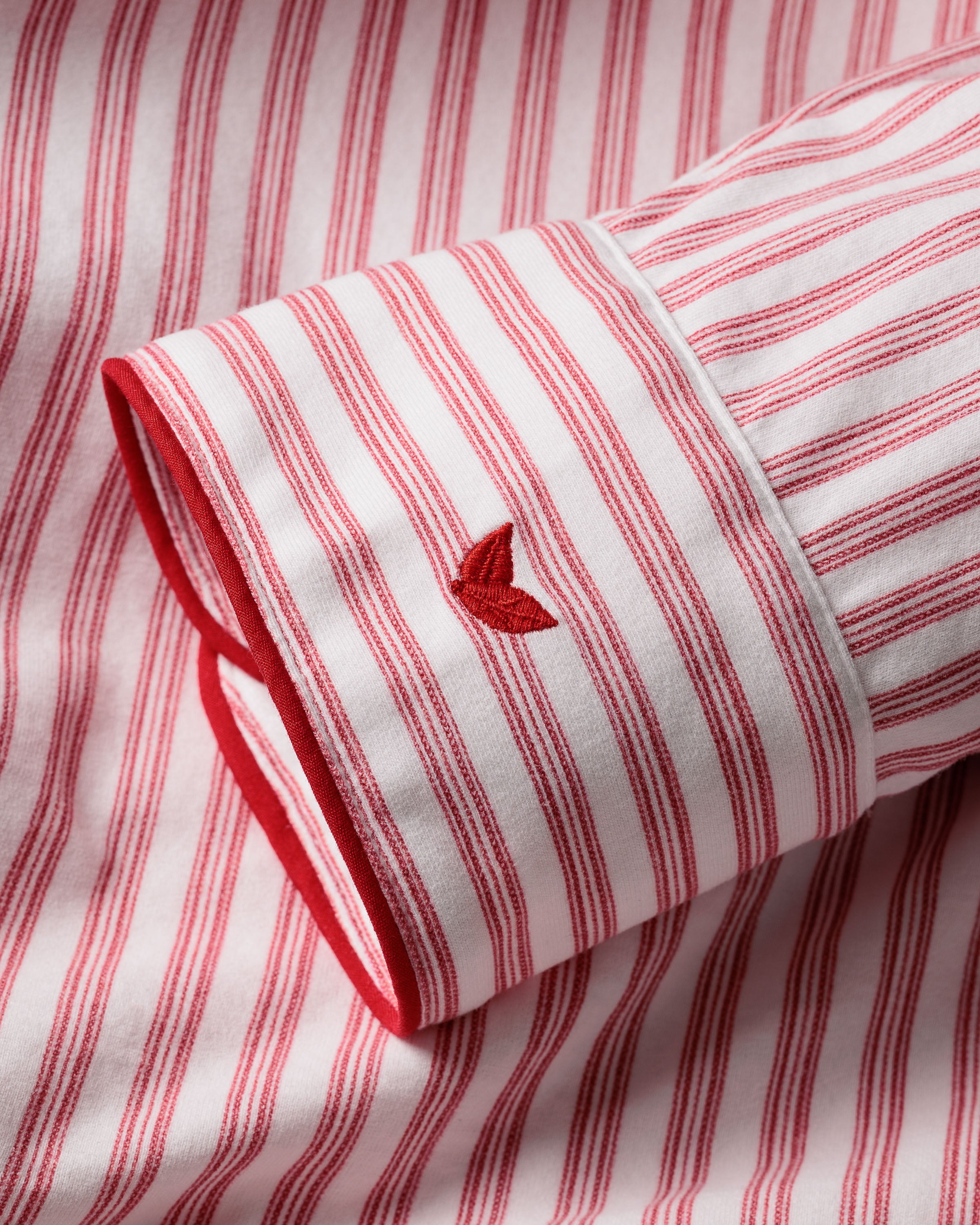 Close-up of a red and white striped sleeve crafted from soft Pima cotton in the Mens Pima Pajama Set in Antique Red Ticking by Petite Plume, featuring embroidered detailing and precise tailoring for timeless pajama luxury.