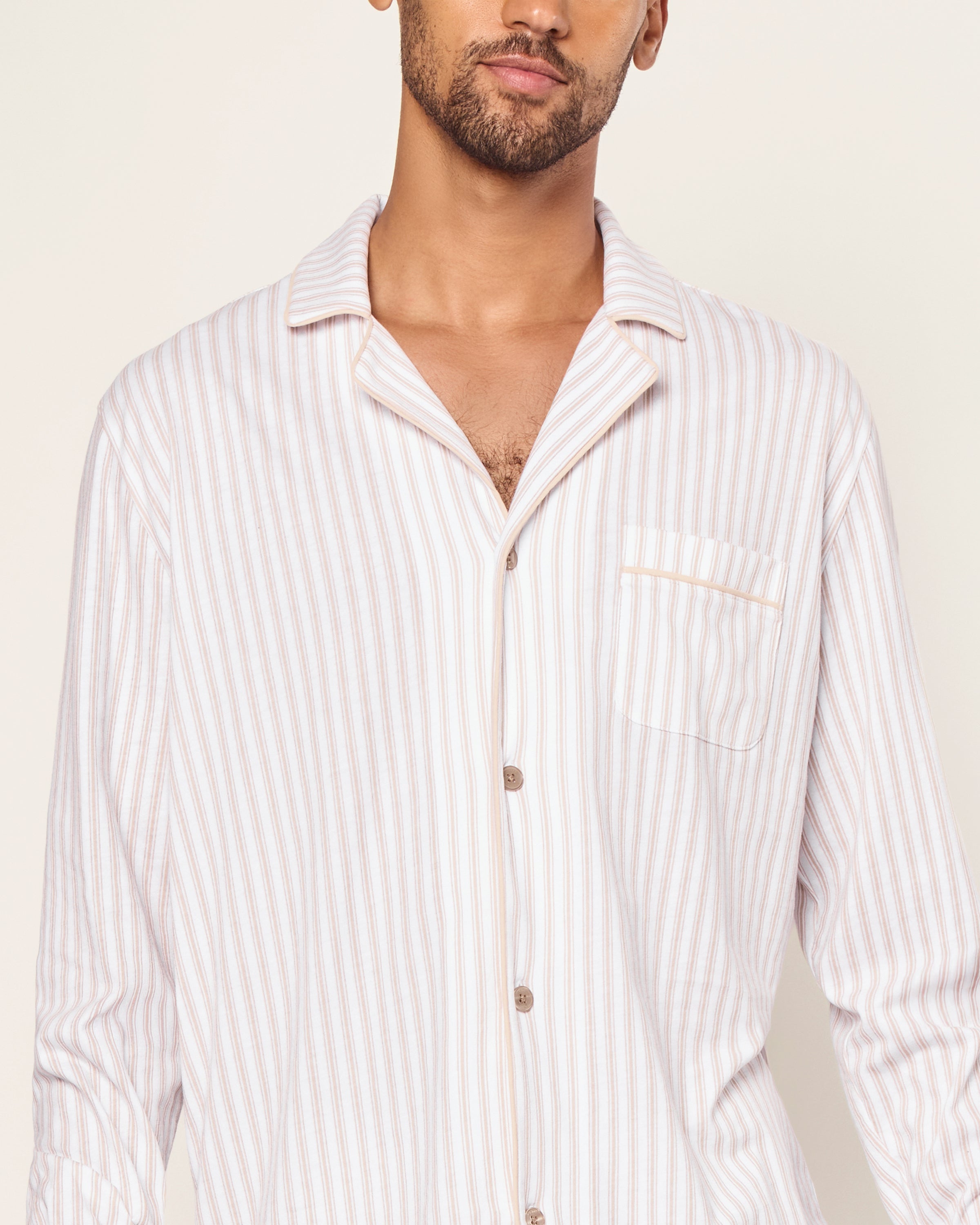 The Men's Pima Pajama Set in Camel Ticking features beige and white stripes, a button-up long-sleeve top with a chest pocket, and matching drawstring pants, displayed flat on a white background.