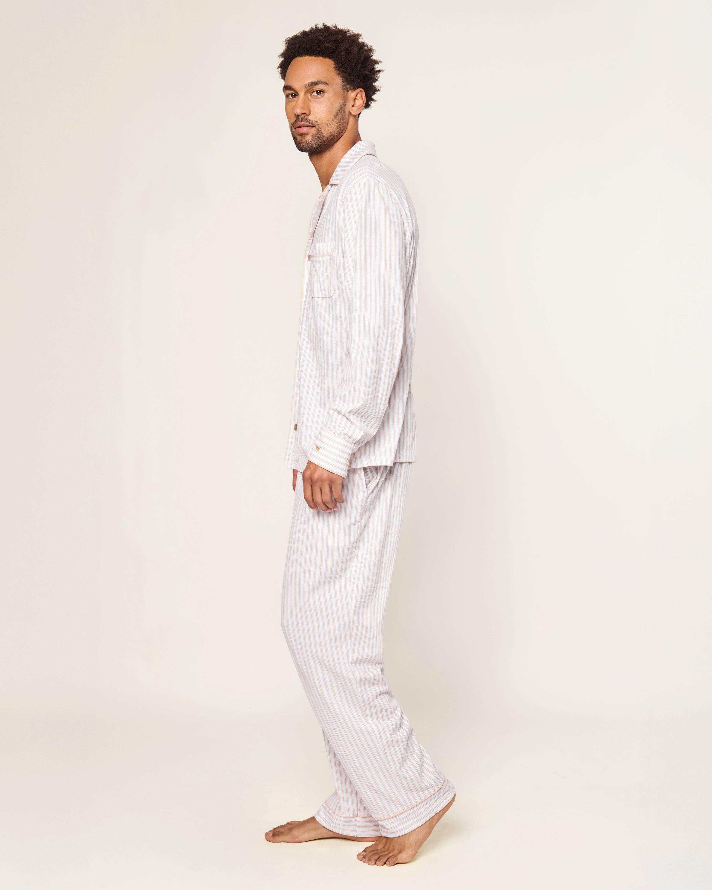 The Men's Pima Pajama Set in Camel Ticking features beige and white stripes, a button-up long-sleeve top with a chest pocket, and matching drawstring pants, displayed flat on a white background.