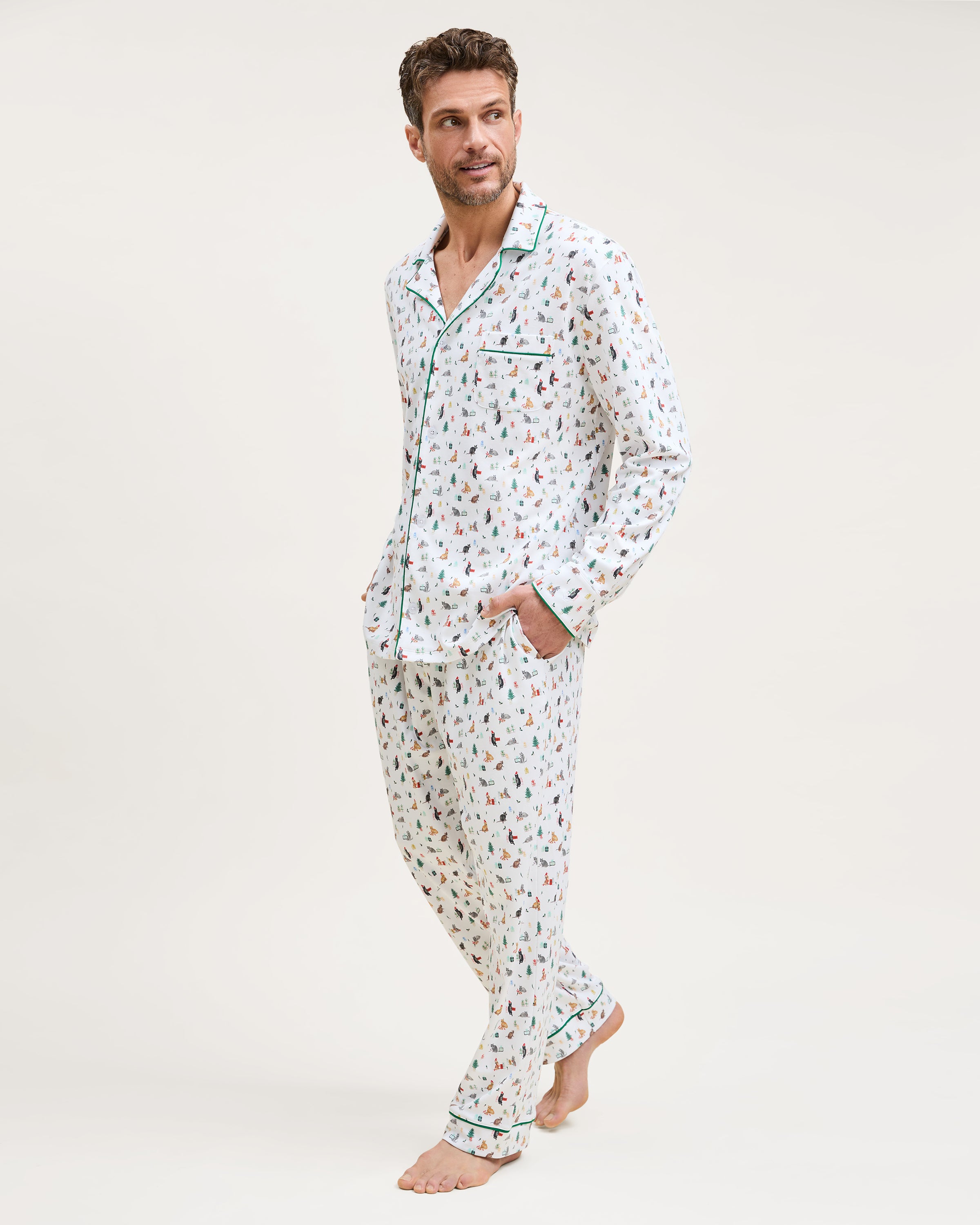 Men's Pima Pajama Set in Merry Meow: white set with green piping, featuring an all-over print of playful colorful cats. Includes a long-sleeve button-up shirt with chest pocket and matching pants.