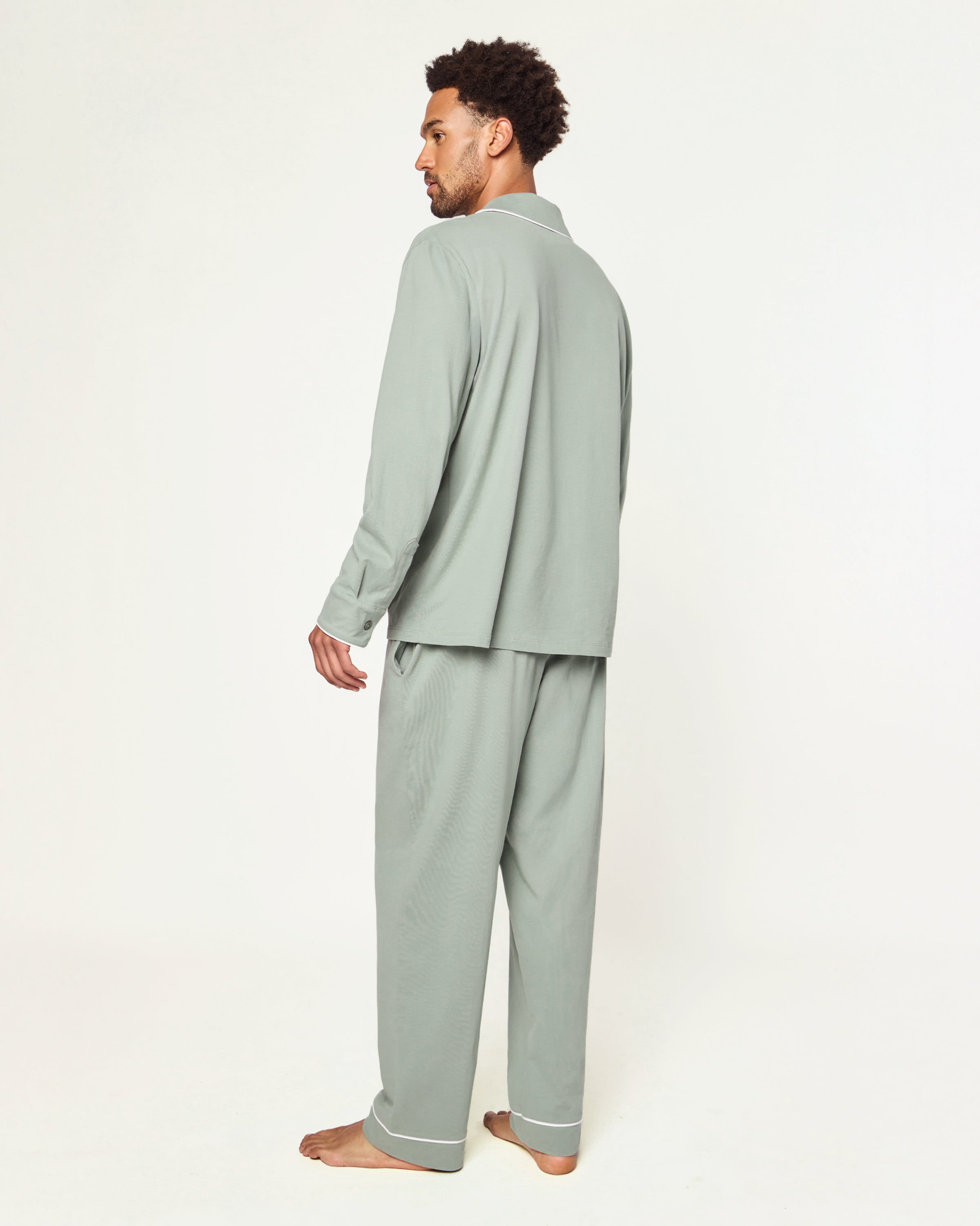 Men’s Pima Pajama Set in Sage: long-sleeve button-up top with white piping and chest pocket, plus matching drawstring pants, both laid flat on a white background.