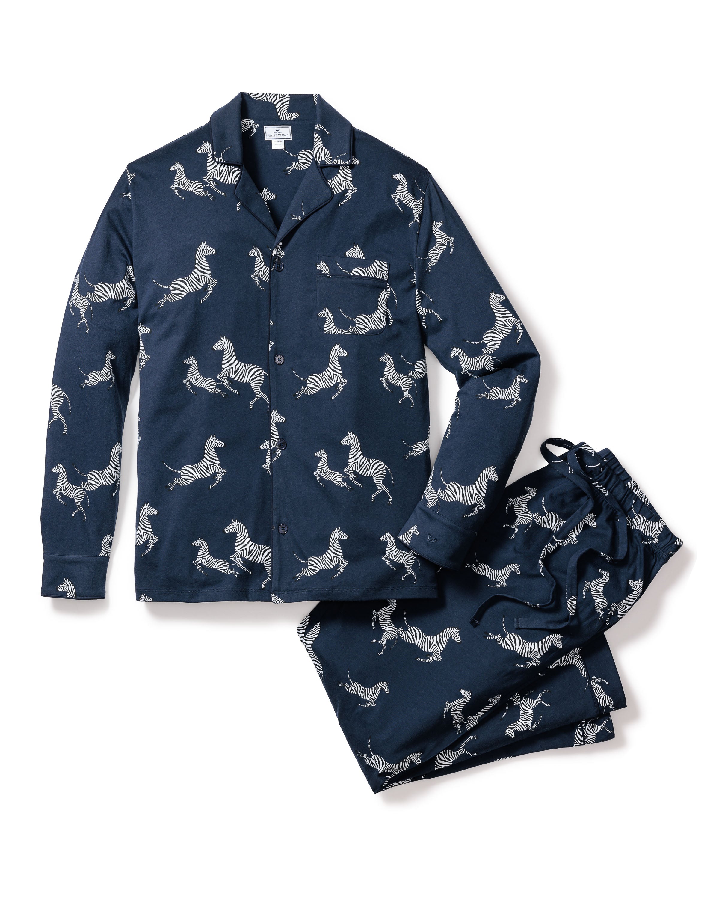 Petite Plumes Mens Pima Pajama Set in Zèbre de Nuit includes a navy blue, long-sleeve button-up shirt with a front pocket and drawstring pants, adorned with a white zebra print.