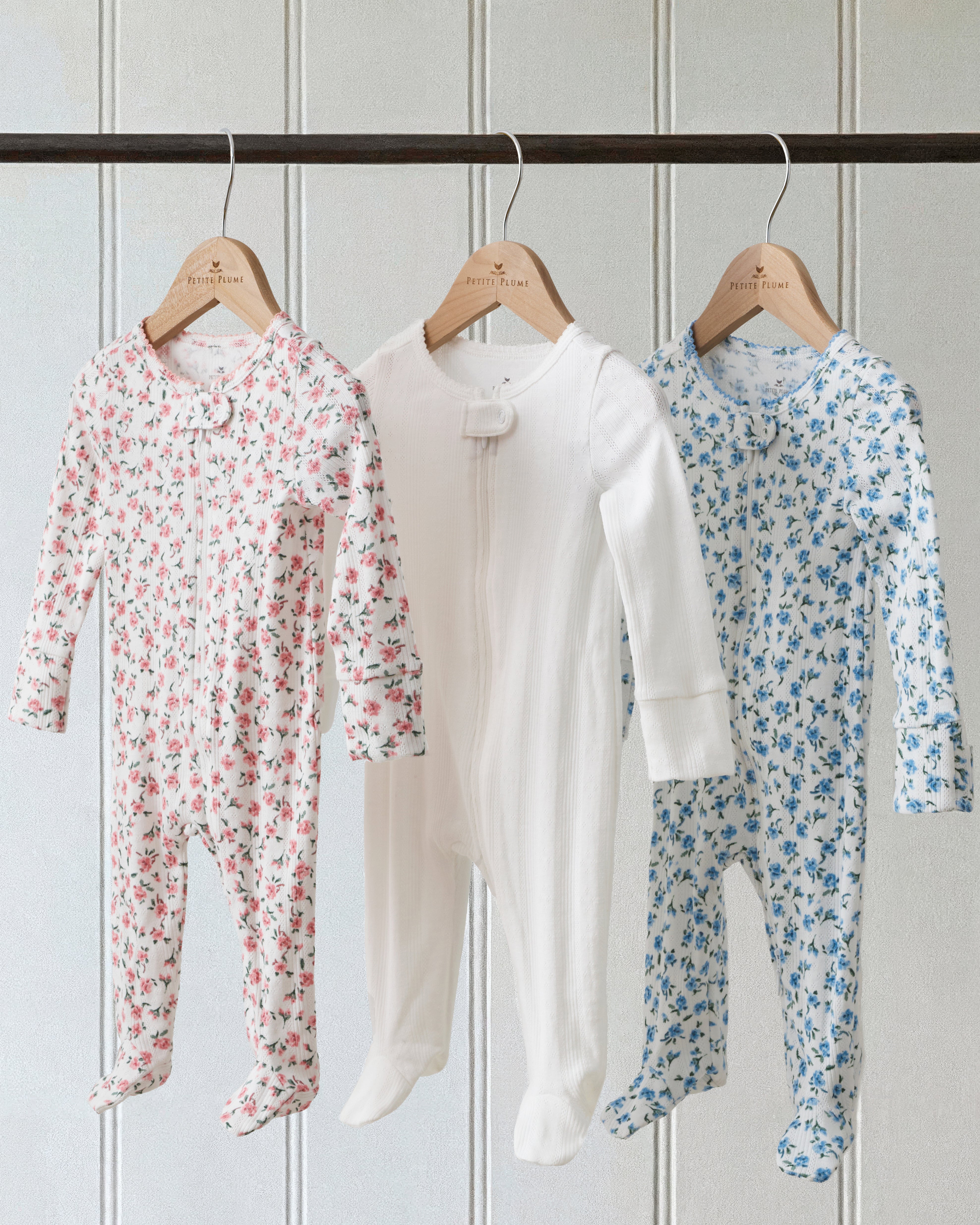 Baby's Pointelle Footie Romper in Pink Floral features a white long-sleeve footed onesie with a pink and green floral print, shown flat on a white background.