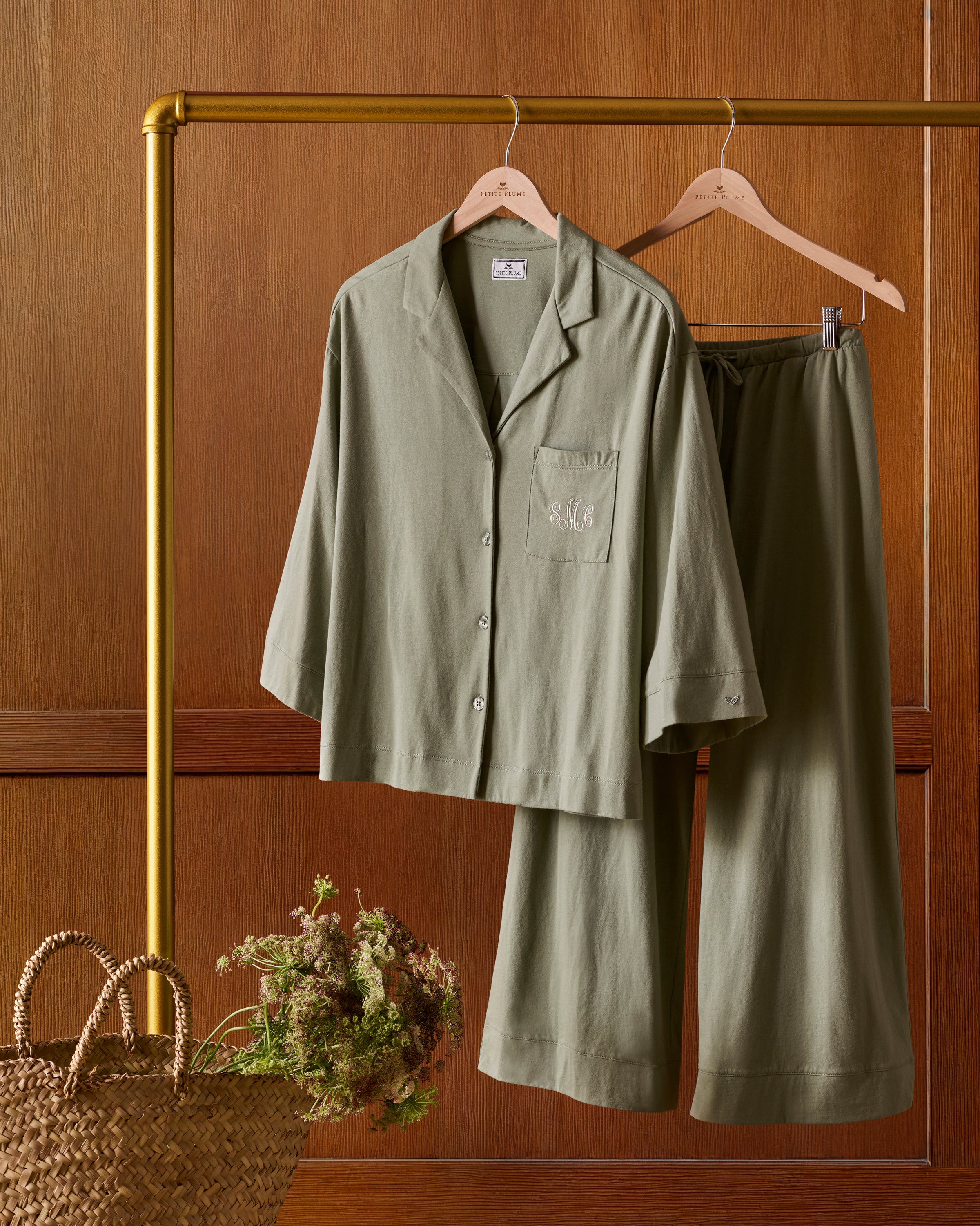 The Olivia Wide Leg Pima Pajama Set in Sage includes a button-up, collared top with a chest pocket and three-quarter sleeves, plus matching elastic waist wide-leg pants. Both pieces are neatly laid flat on a white background.