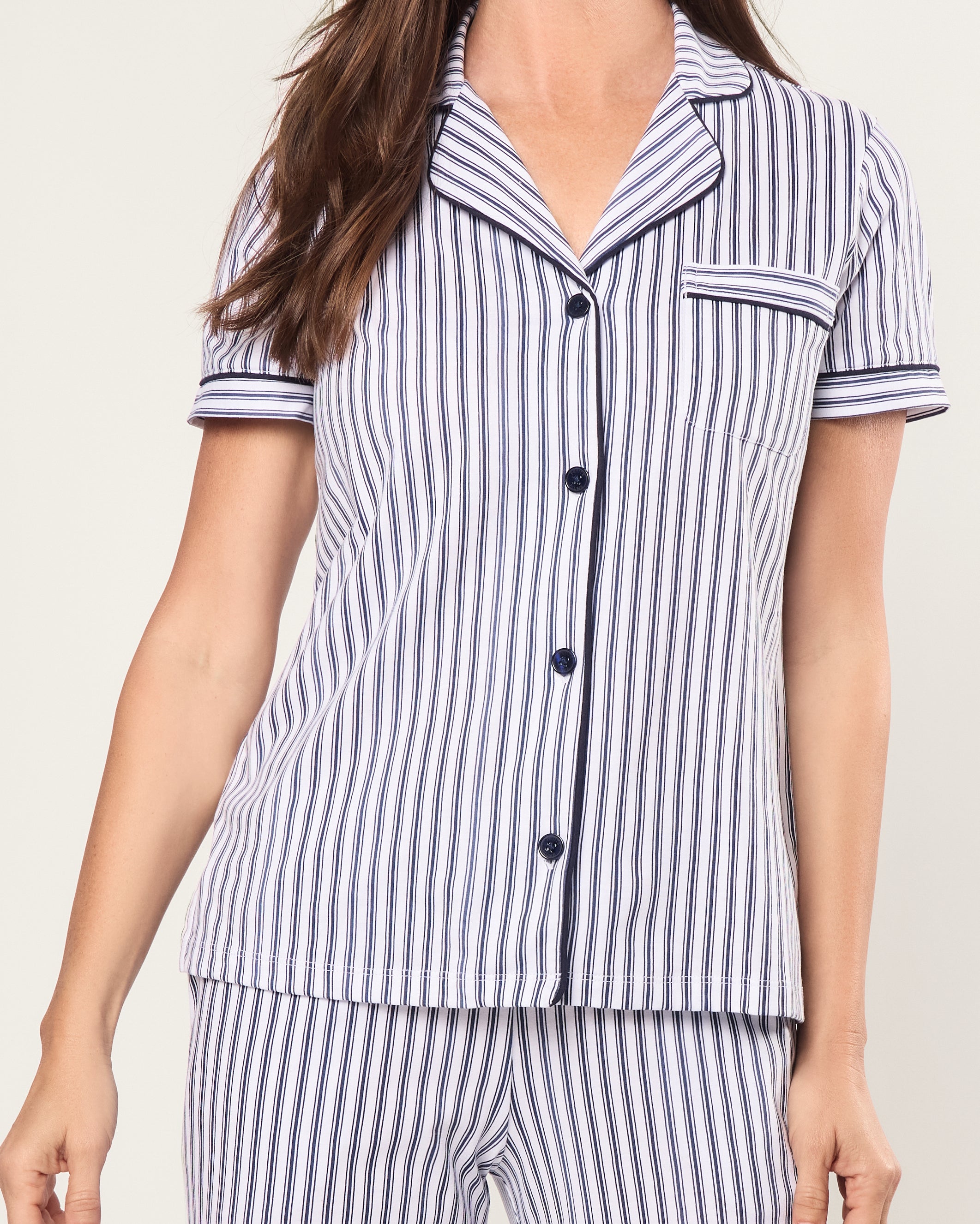 The Women's Pima Crop Pajama Set in Navy French Ticking features a blue and white vertical stripe design, short sleeves, a collared button-up top with chest pocket, and matching long pants.