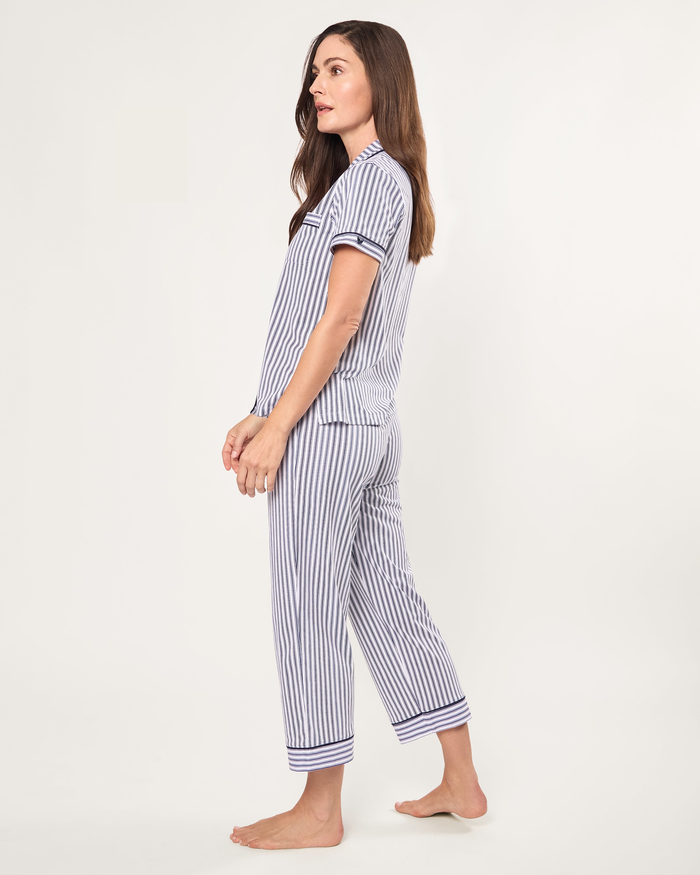 The Women's Pima Crop Pajama Set in Navy French Ticking features a blue and white vertical stripe design, short sleeves, a collared button-up top with chest pocket, and matching long pants.