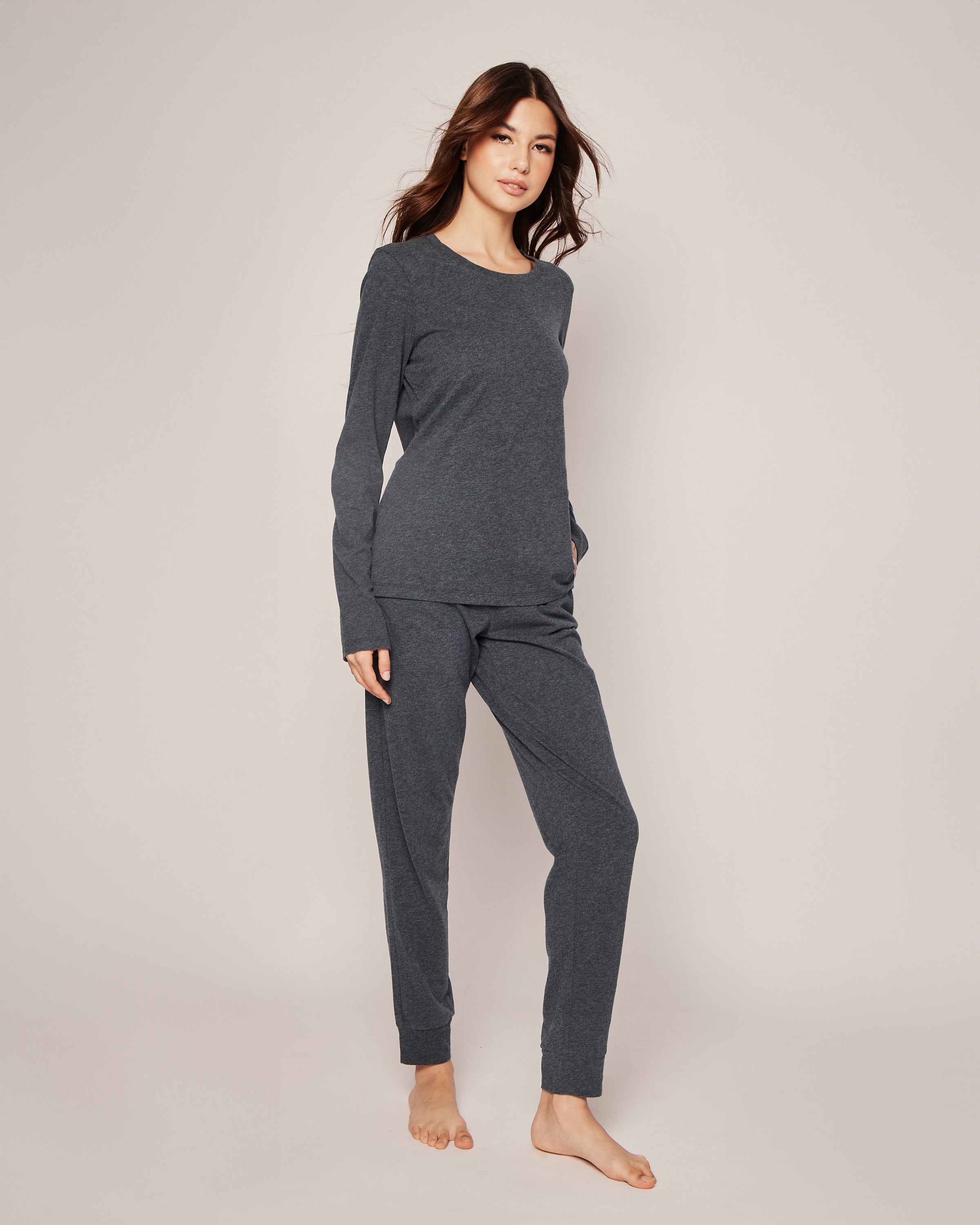 A person with long hair wears Petite Plumes Womens Pima Lounge Pants in Dark Heather Grey, made from 100% Peruvian Pima cotton. Barefoot on a neutral background, they exude elegance and comfort.