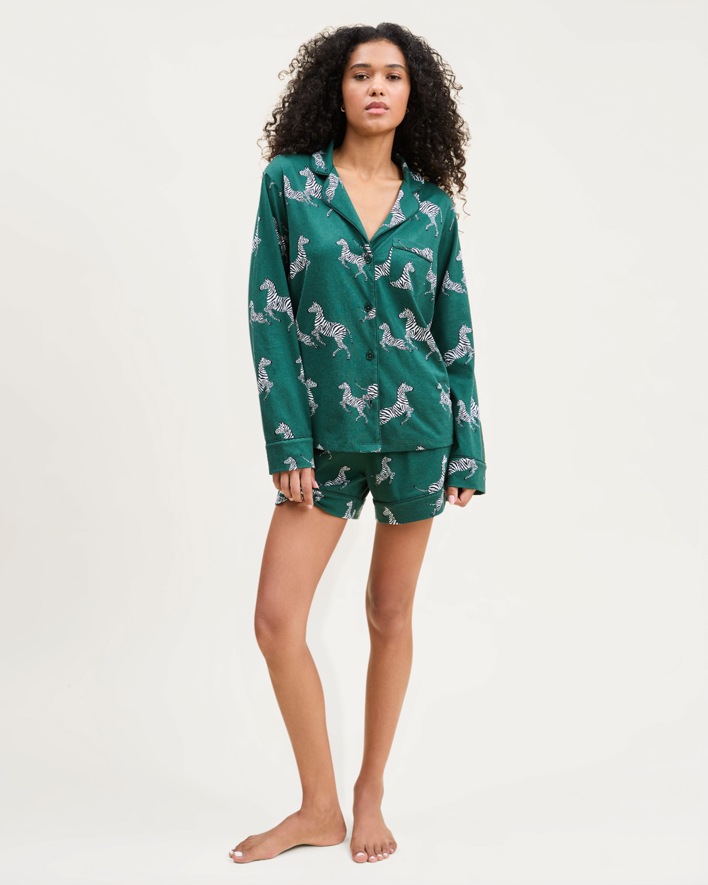 The Women's Pima Long Sleeve Short Set in Zèbre de Forêt features a green button-up shirt and matching shorts, both adorned with an allover playful white zebra print.