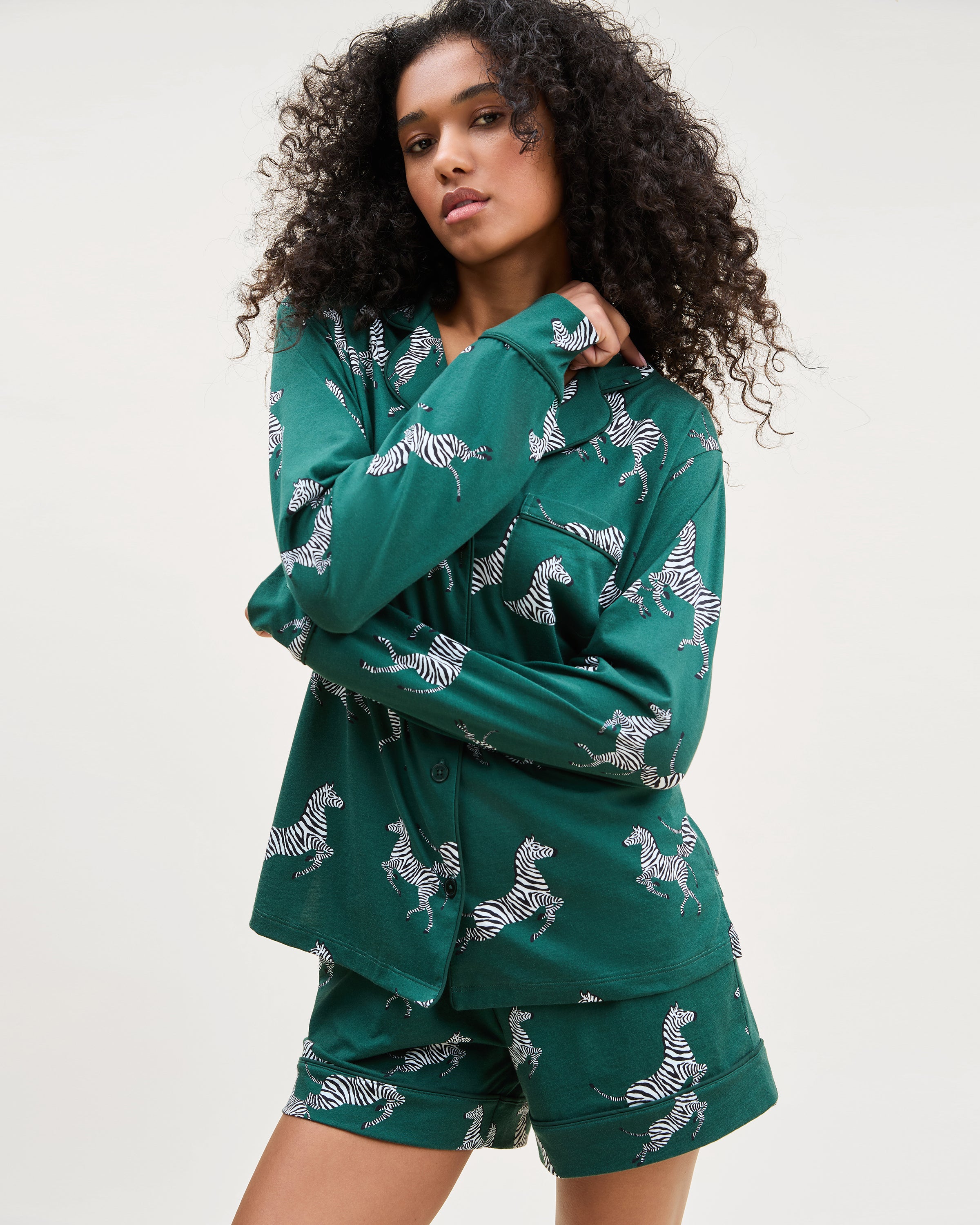 The Women's Pima Long Sleeve Short Set in Zèbre de Forêt features a green button-up shirt and matching shorts, both adorned with an allover playful white zebra print.