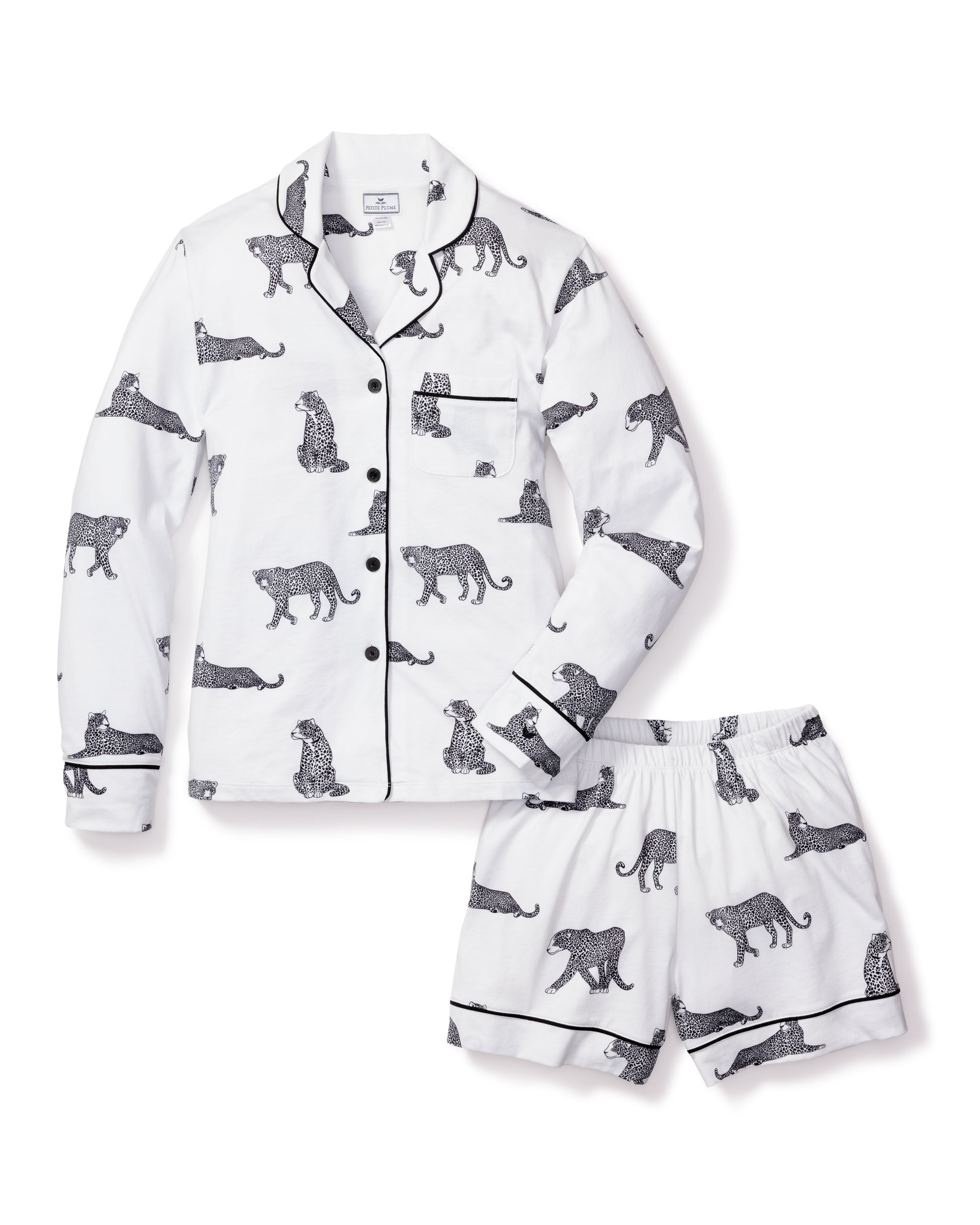 The Womens Pima Short Set in Panthère de Paris by Petite Plume is made from luxe white Pima cotton and features a long-sleeve shirt with black piped collar, cuffs, and pocket, paired with shorts adorned in black leopard print with matching trim.