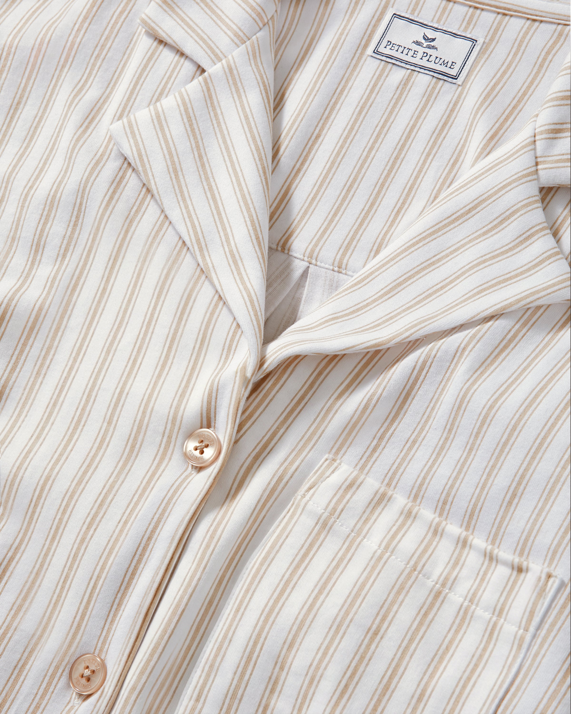 The Olivia Pima Short Set in Camel Ticking features a two-piece pajama set with beige and white vertical stripes, including a button-up, collared long-sleeve shirt with a breast pocket, and matching relaxed-fit drawstring shorts.