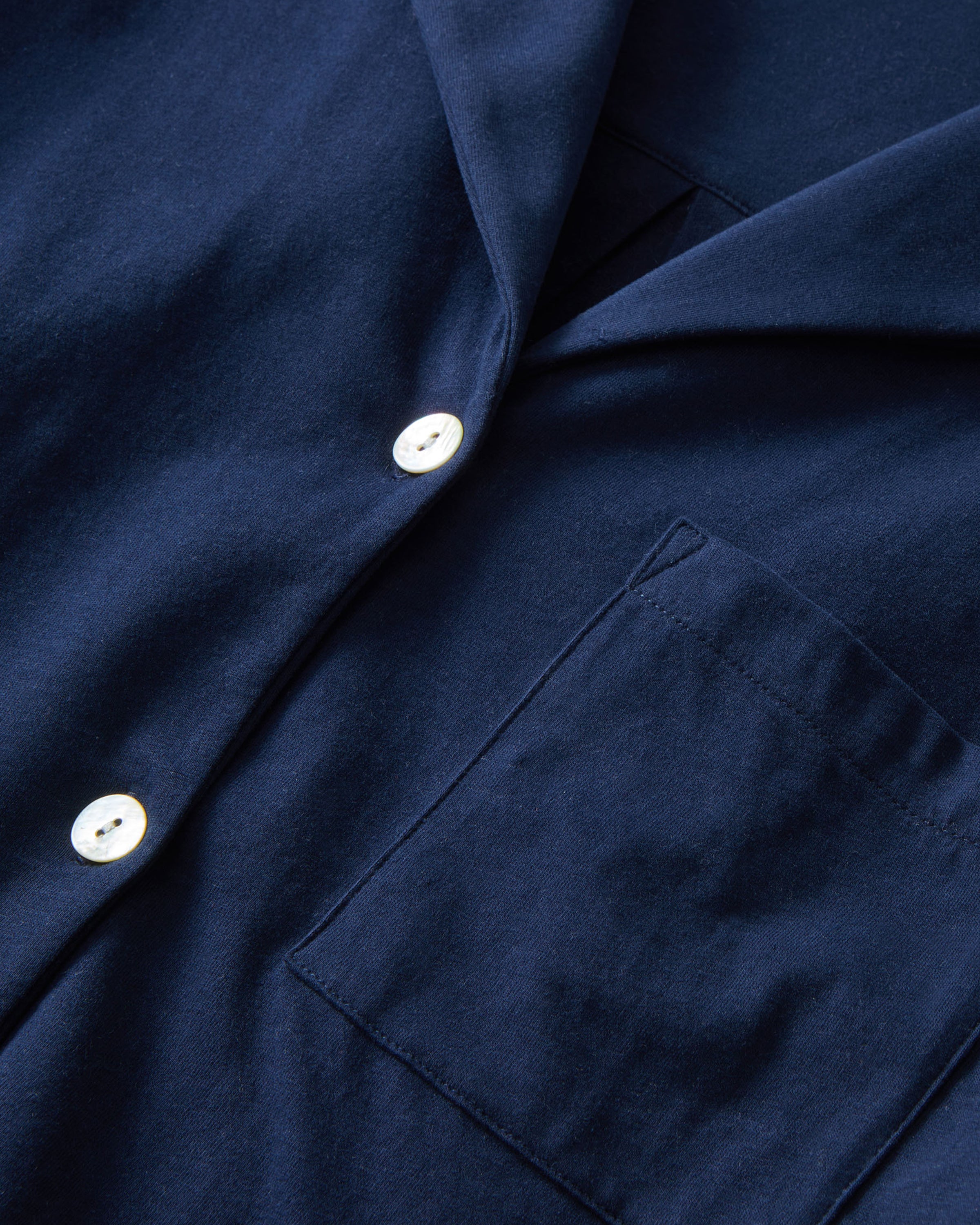 The Olivia Pima Short Set in Navy features a short-sleeve button-up top with a chest pocket and matching drawstring shorts, both displayed flat on a white background.