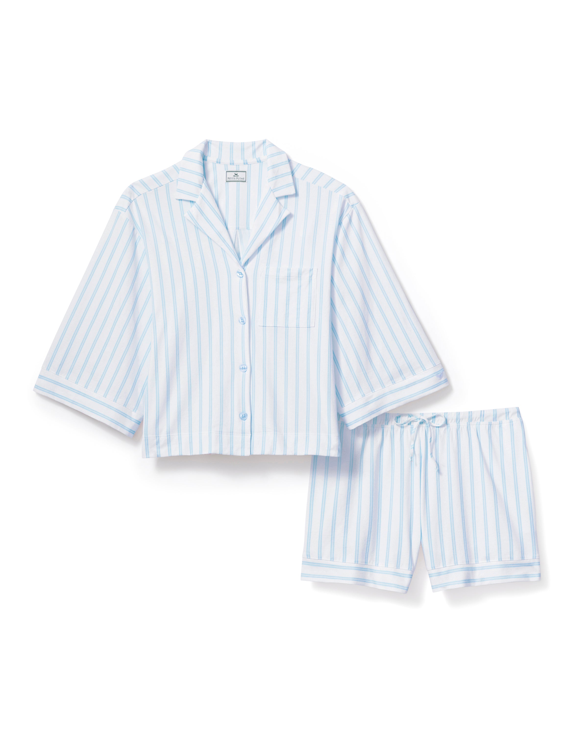 The Olivia Pima Short Set in Periwinkle Stripe features light blue and white vertical stripes, a short-sleeve button-up shirt with a chest pocket, and matching drawstring shorts.