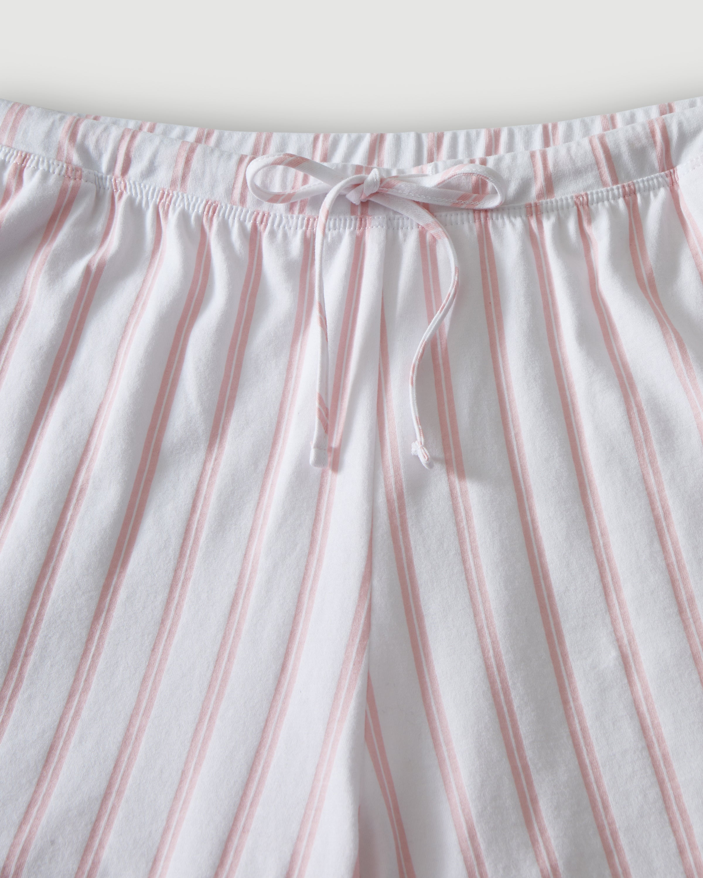 The Olivia Pima Short Set in Pink Stripe features a two-piece pajama set with white and pink vertical stripes, a long-sleeve button-up top with chest pocket, and matching drawstring shorts.