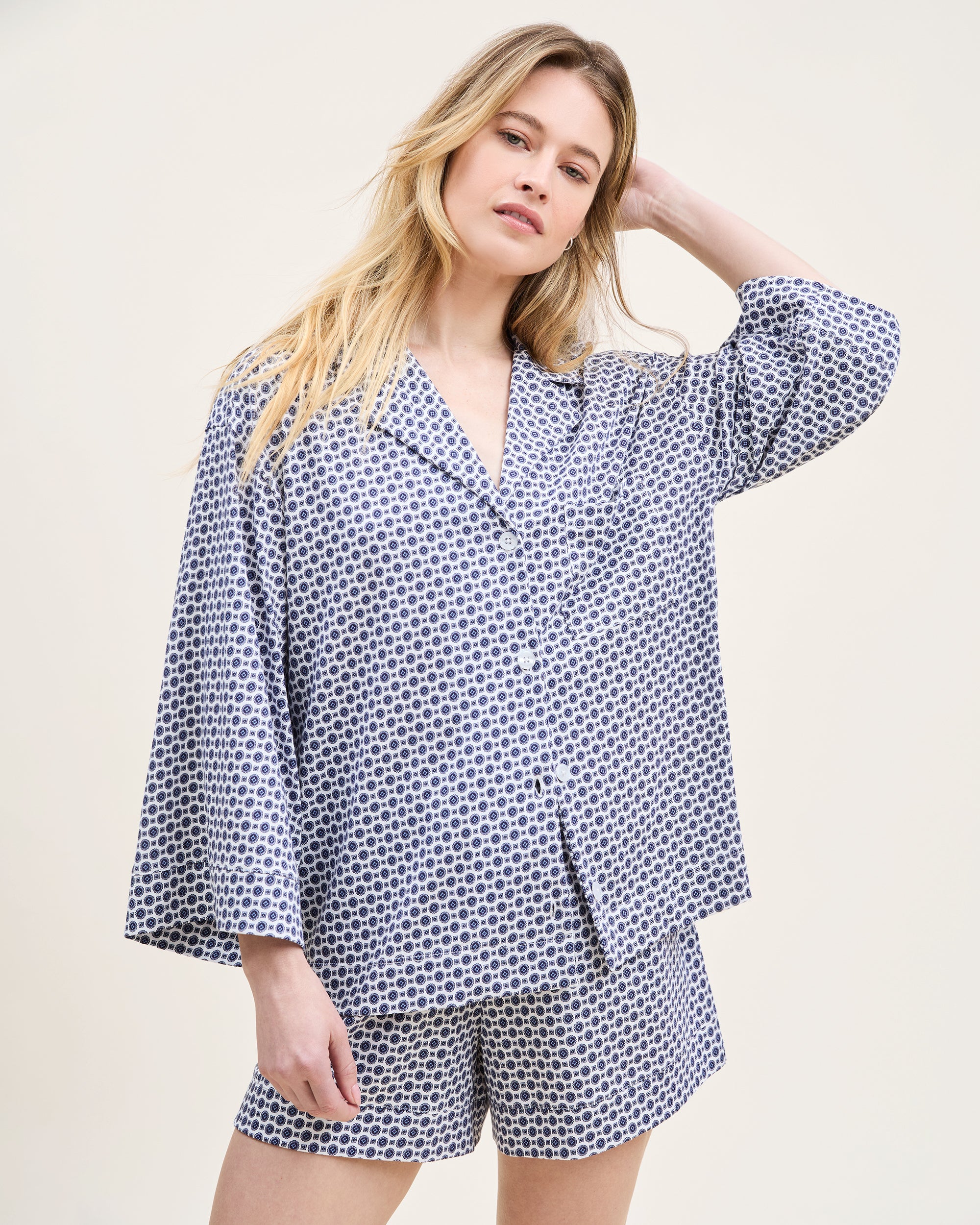 The Olivia Pima Short Set in Navy Foulard features a two-piece pajama set with a blue and white geometric pattern, including a button-up short-sleeve collared shirt and matching shorts.