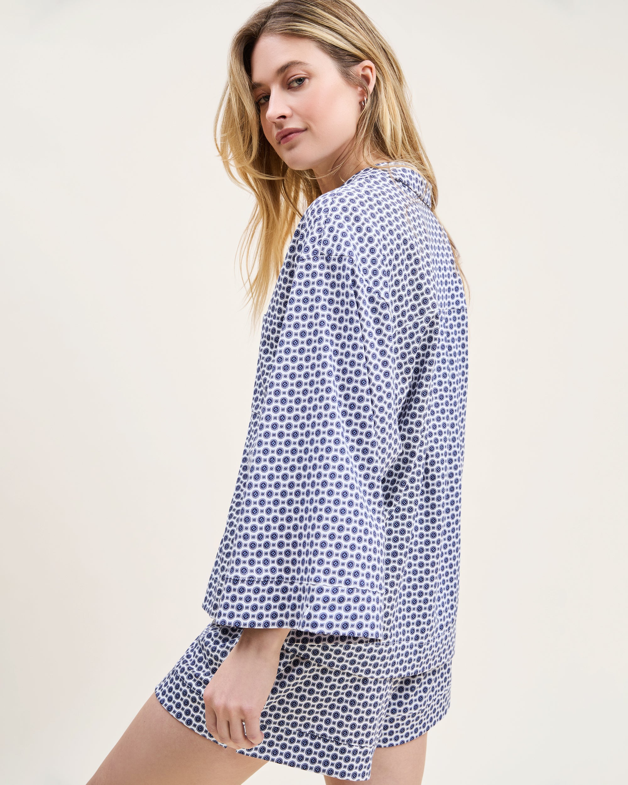 The Olivia Pima Short Set in Navy Foulard features a two-piece pajama set with a blue and white geometric pattern, including a button-up short-sleeve collared shirt and matching shorts.