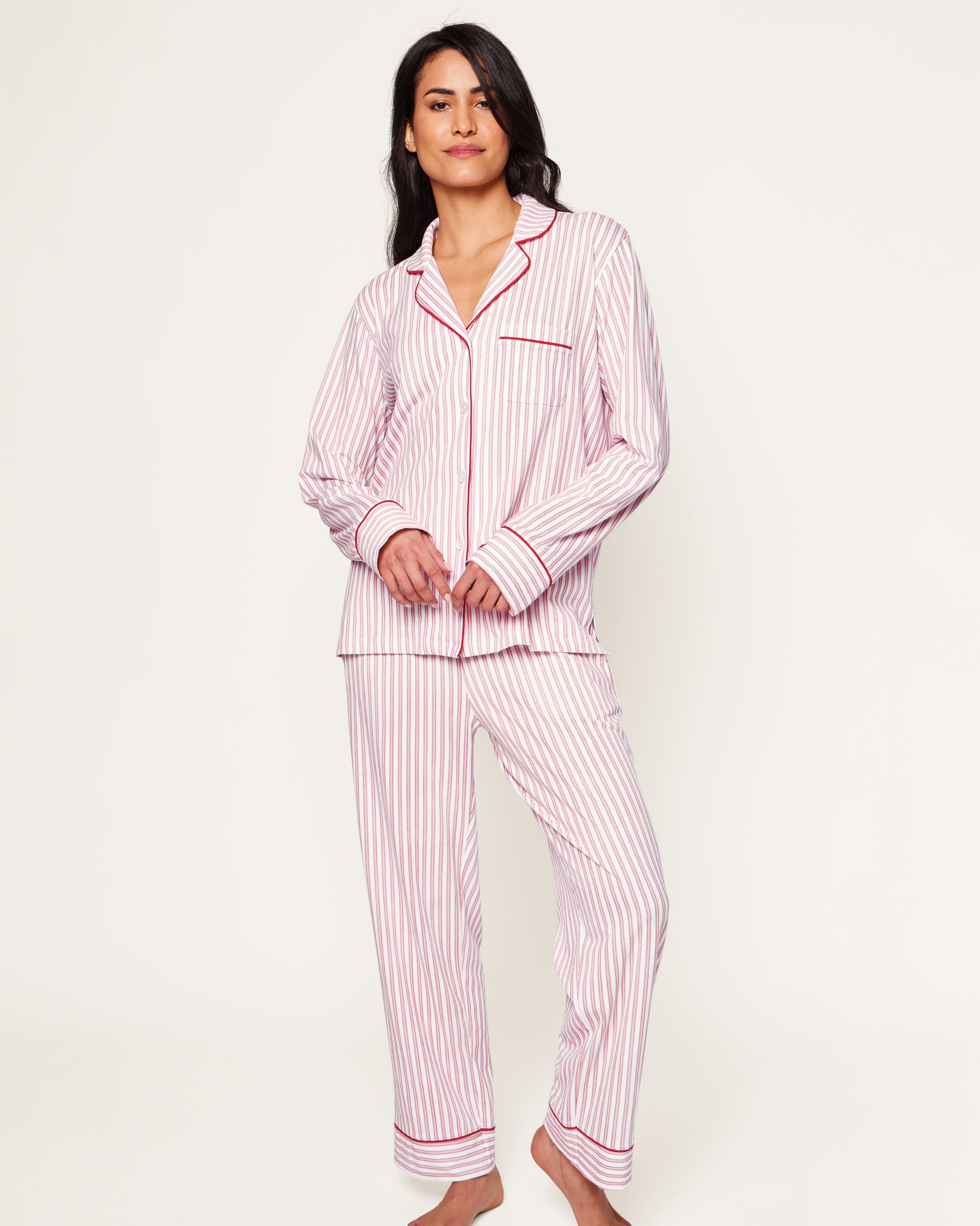 Close-up of Petite Plumes Womens Pima Pajama Set in Antique Red Ticking, showcasing luxury fabric with red and white vertical stripes. The image reveals part of the garment with a white button, collar, and pocket trimmed in red, hinting at its soft and cozy Peruvian Pima cotton.