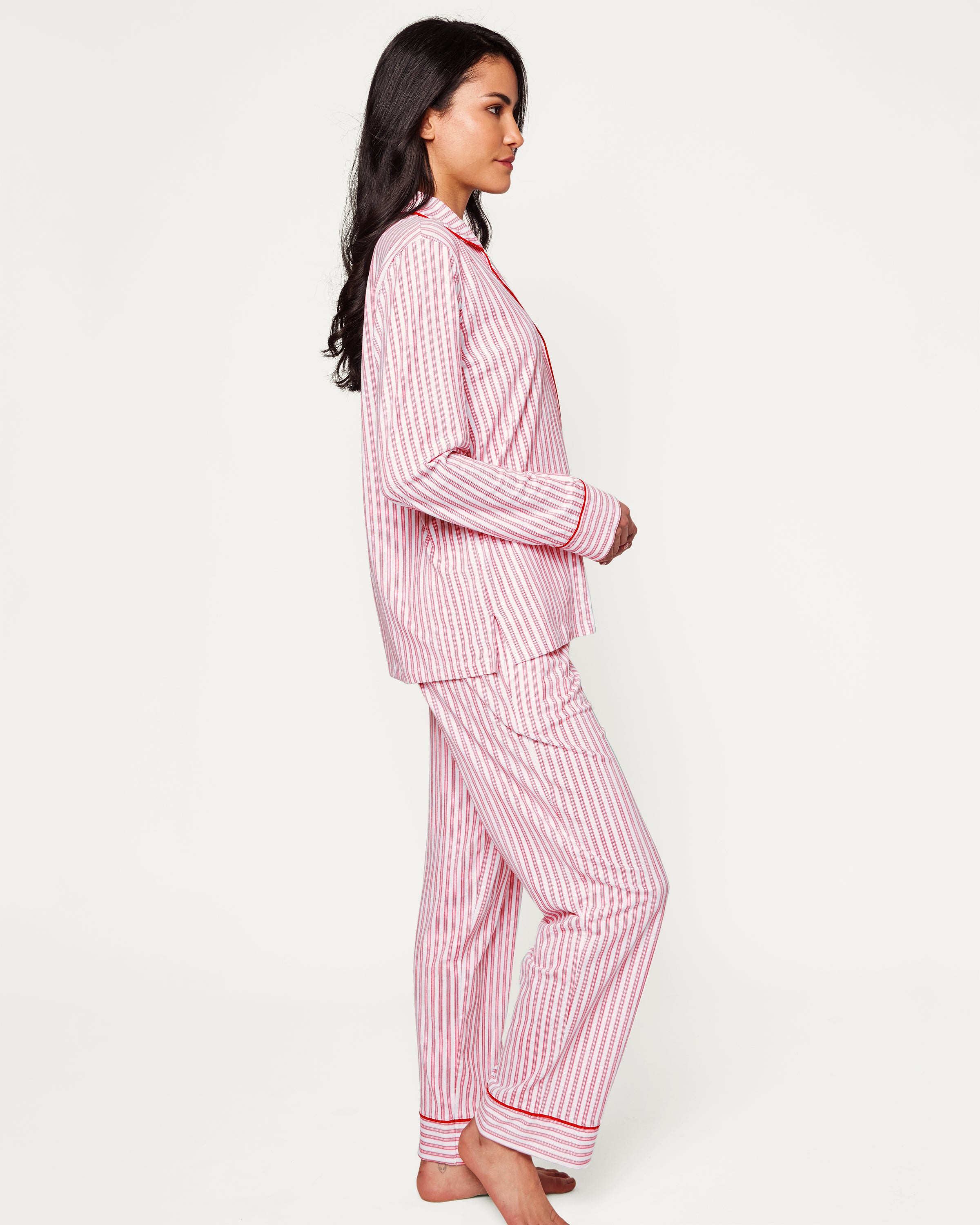 Close-up of Petite Plumes Womens Pima Pajama Set in Antique Red Ticking, showcasing luxury fabric with red and white vertical stripes. The image reveals part of the garment with a white button, collar, and pocket trimmed in red, hinting at its soft and cozy Peruvian Pima cotton.