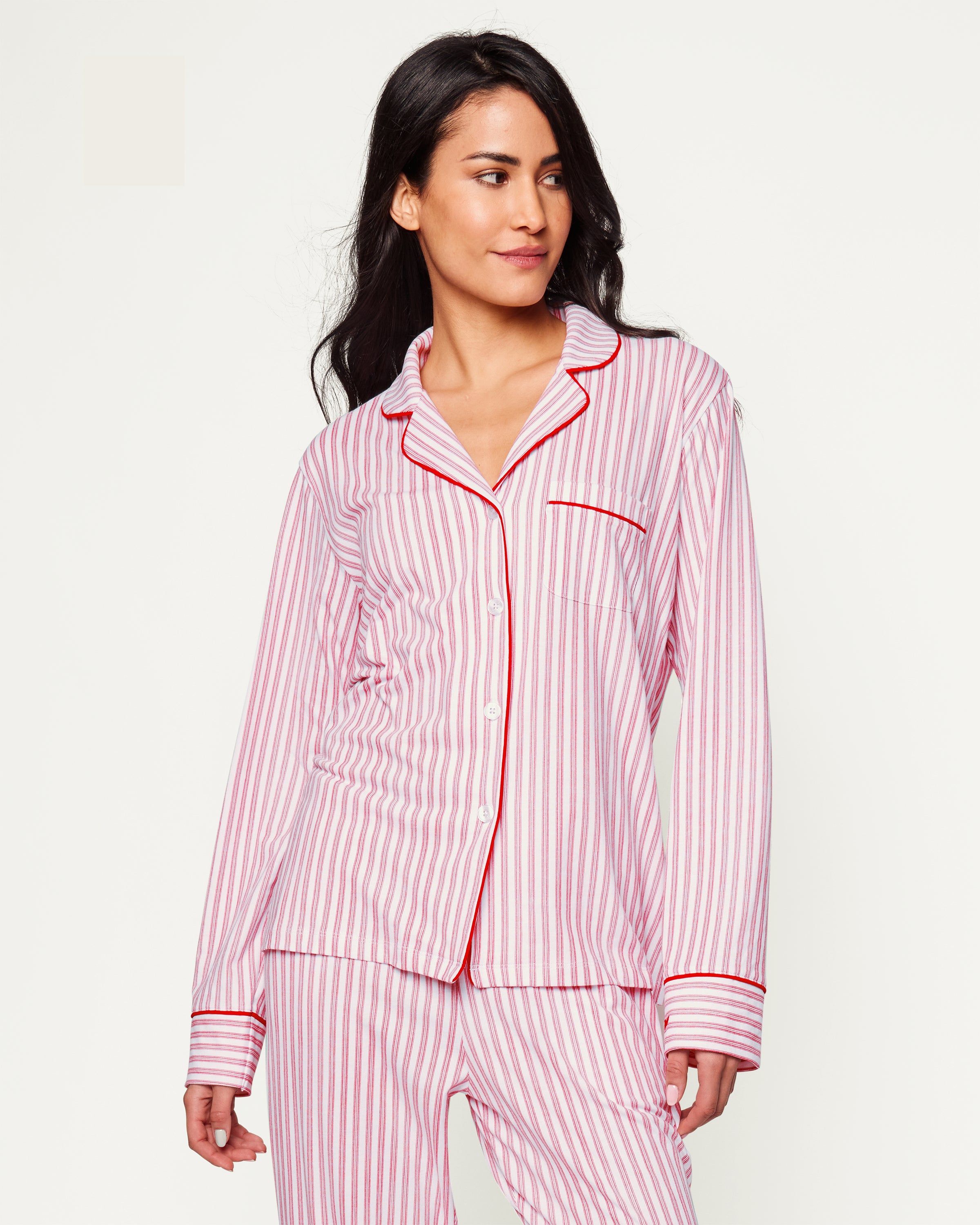 Close-up of Petite Plumes Womens Pima Pajama Set in Antique Red Ticking, showcasing luxury fabric with red and white vertical stripes. The image reveals part of the garment with a white button, collar, and pocket trimmed in red, hinting at its soft and cozy Peruvian Pima cotton.