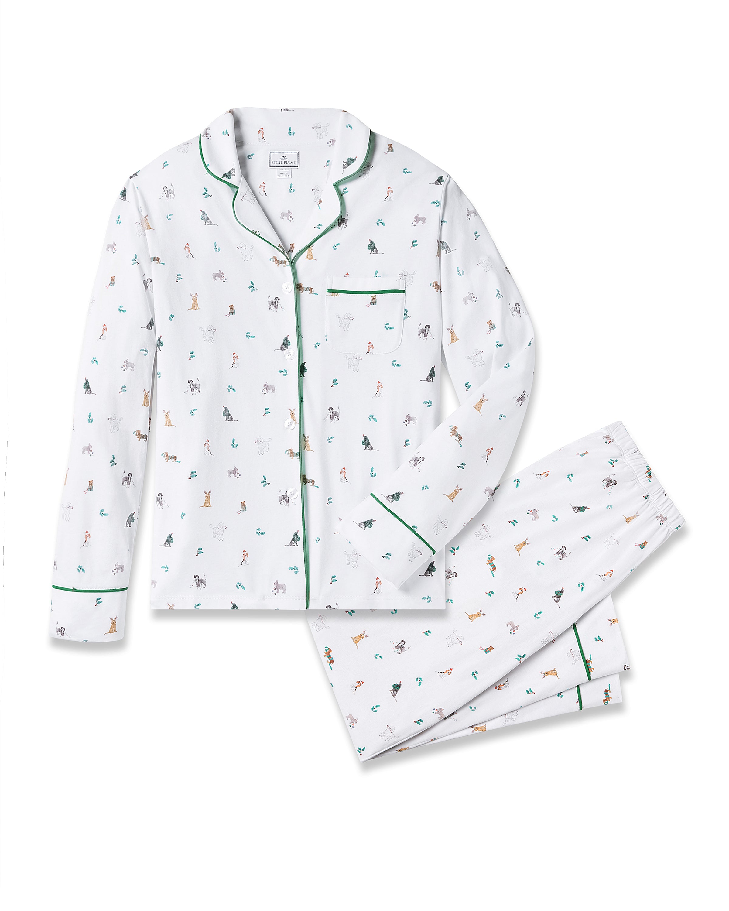 Dressed in Petite Plumes Womens Pima Pajama Set in Jingle Paws, an individual with long hair stands against a neutral backdrop. The luxurious pajamas, accented with green piping, feature an animal print and embody holiday sleepwear elegance as they place hands in pockets.