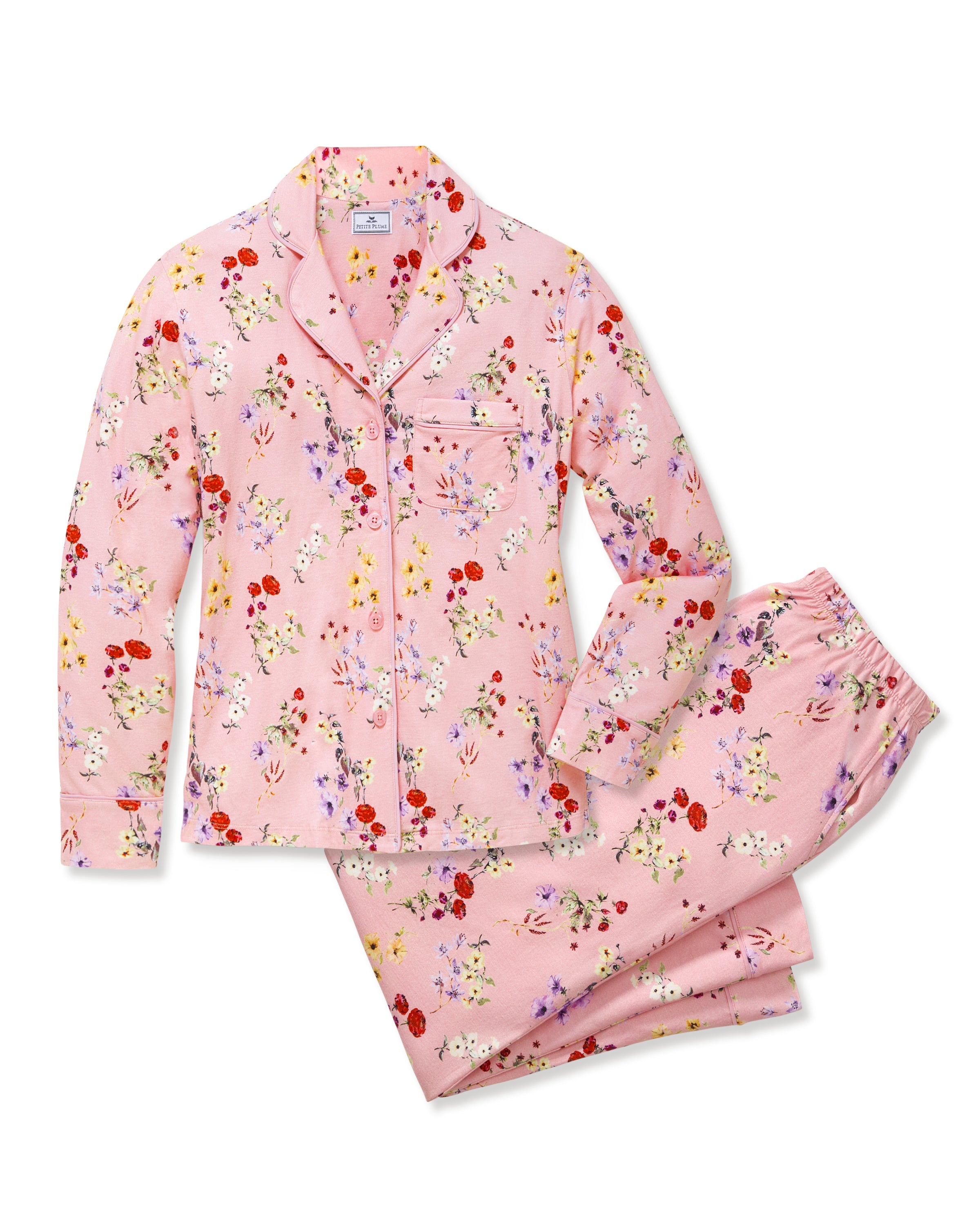 The Women's Pima Pajama Set in Brilliant Botanical Blush features a pink button-up long-sleeve top and matching pants, both adorned with a vibrant floral print in red, white, and purple.