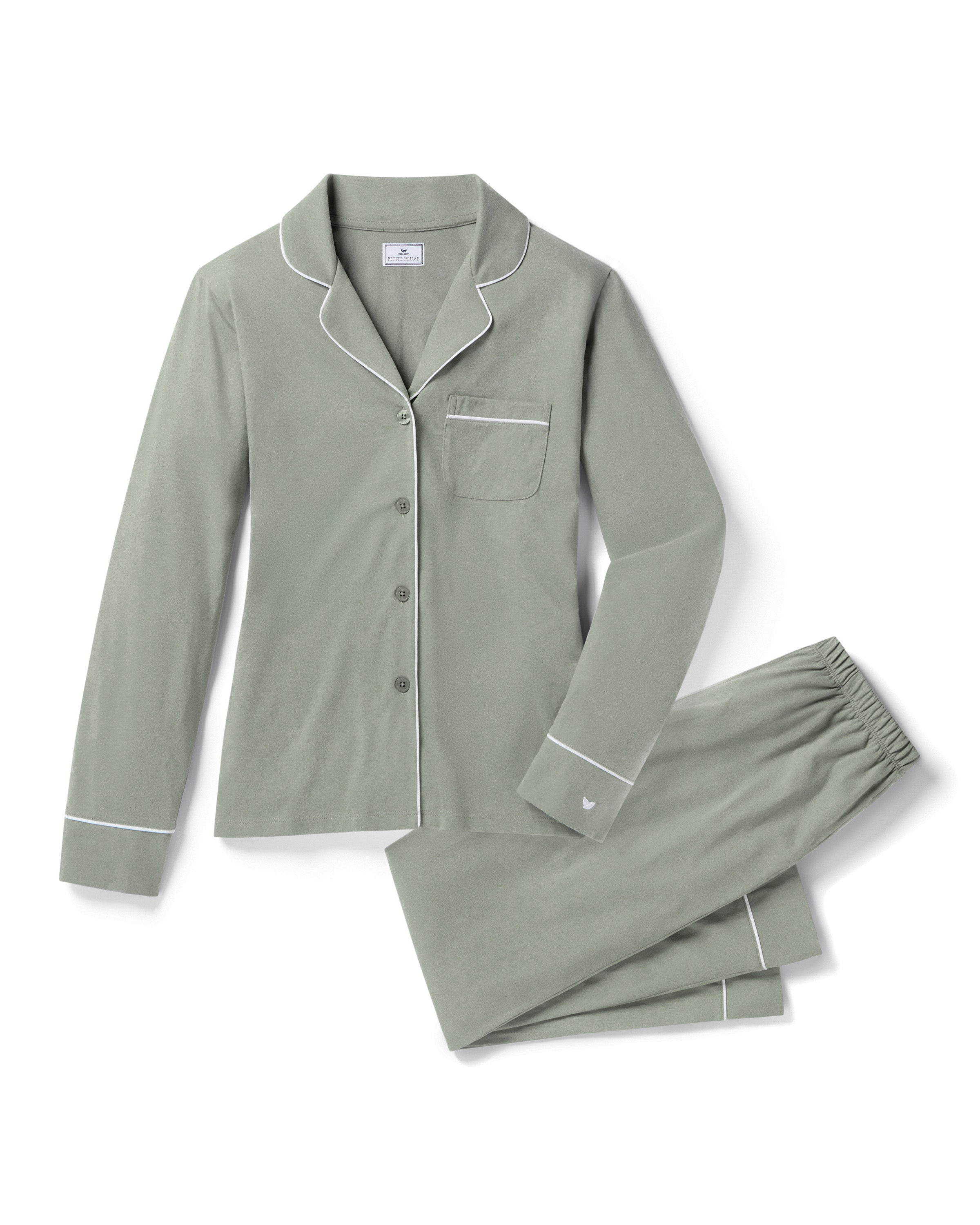 The Women's Pima Pajama Set in Sage features a light green two-piece design with white piping, a long-sleeve button-up top with a chest pocket, and matching pants with an elastic waistband, shown on a white background.