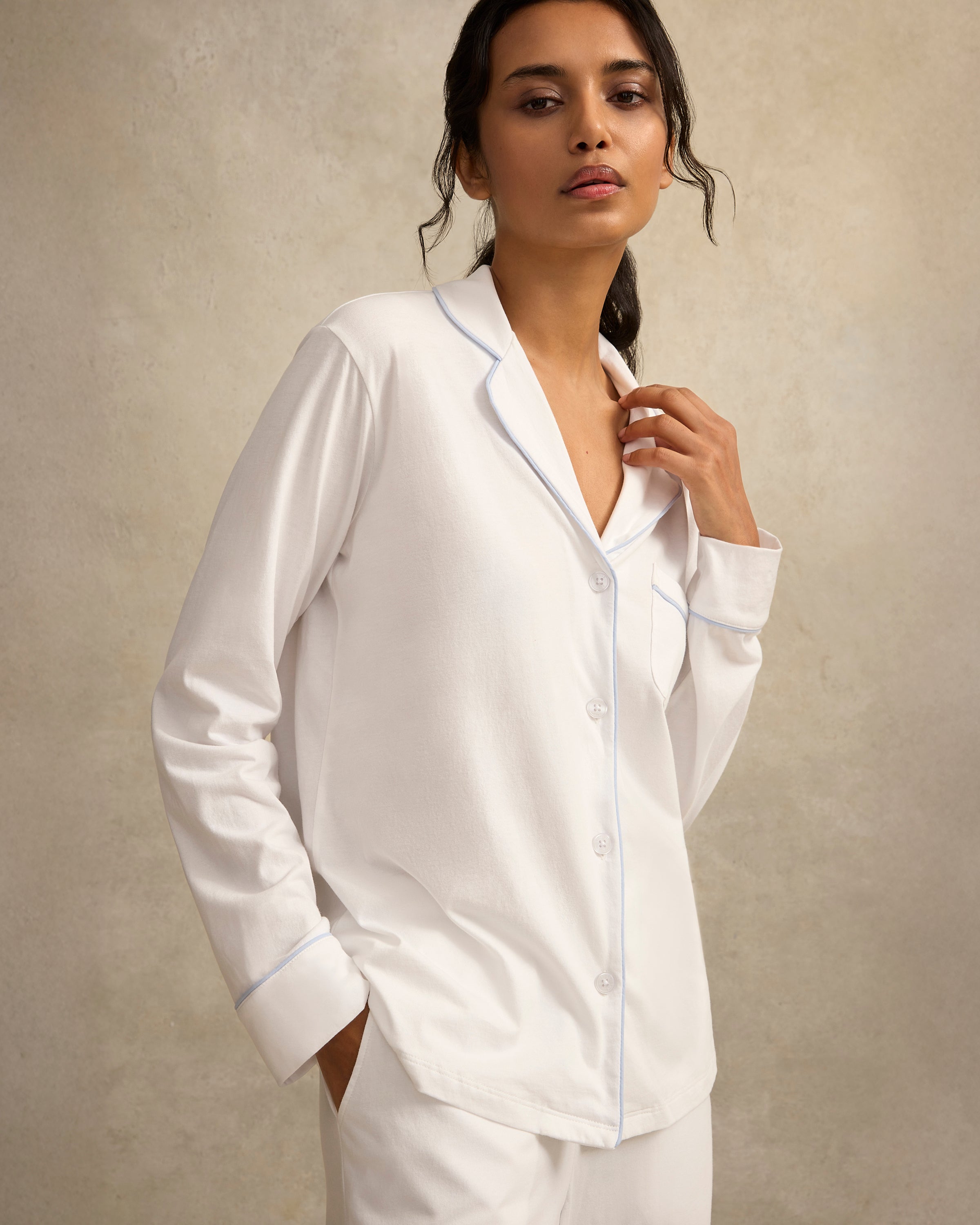 Woman wearing a white satin pajama set against a beige background