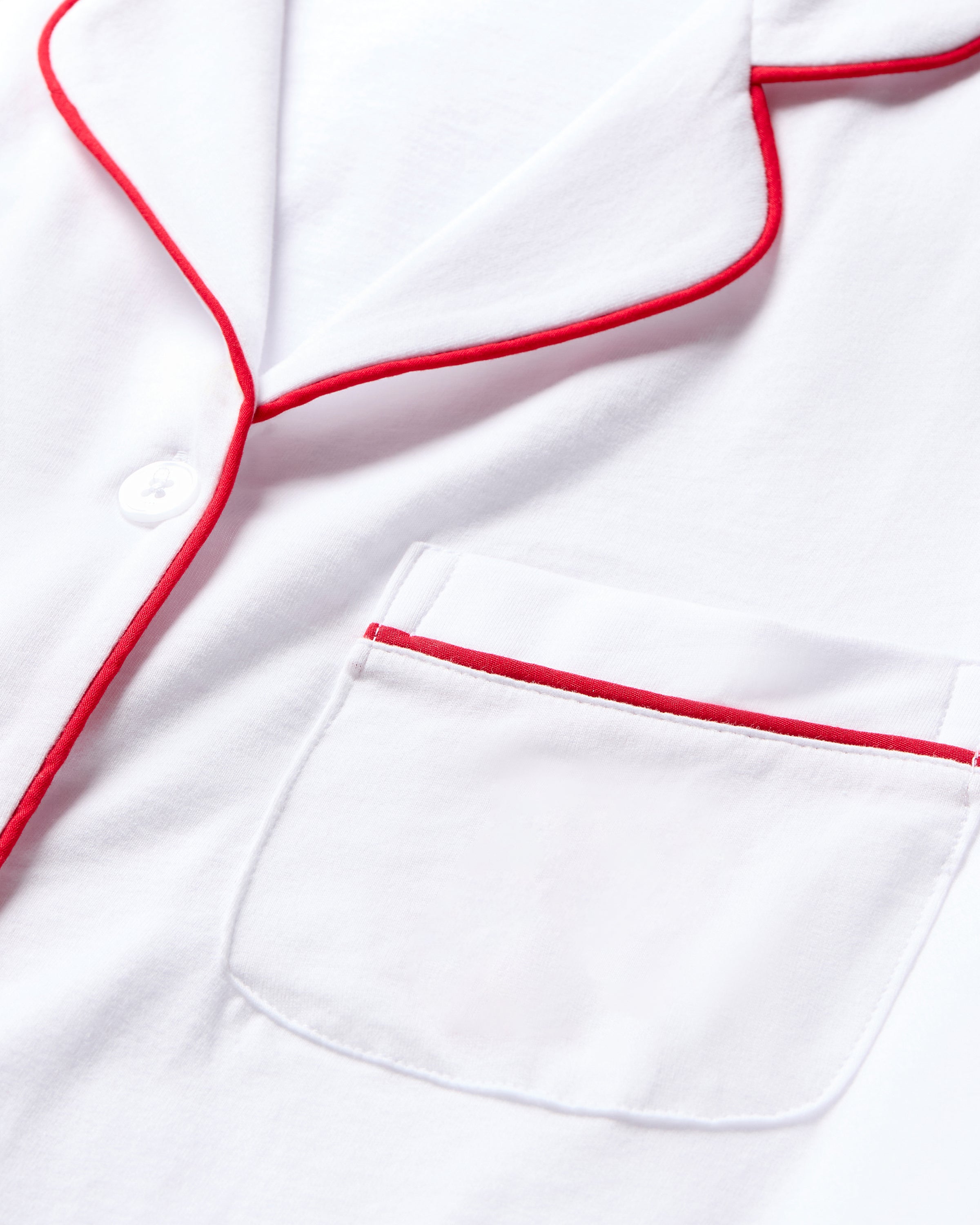 Close-up of the Womens White Pima Pajama Set with Red Piping by Petite Plume, highlighting the front pocket. Made from Peruvian Pima cotton, this button-down design with a visible collar embodies a timeless pajama silhouette.