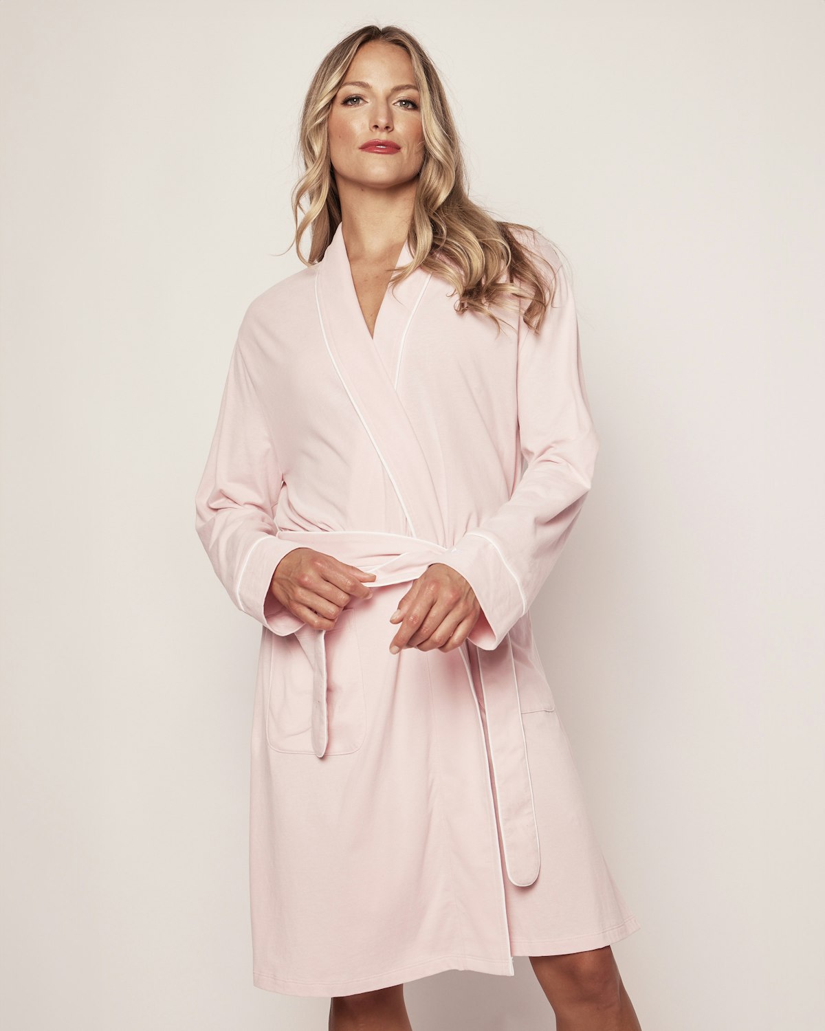 A person with long blonde hair wears a luxurious Petite Plume Womens Pima Robe in Light Heather Grey, featuring a waist-tied belt. They stand confidently against a plain background, gazing directly at the camera.