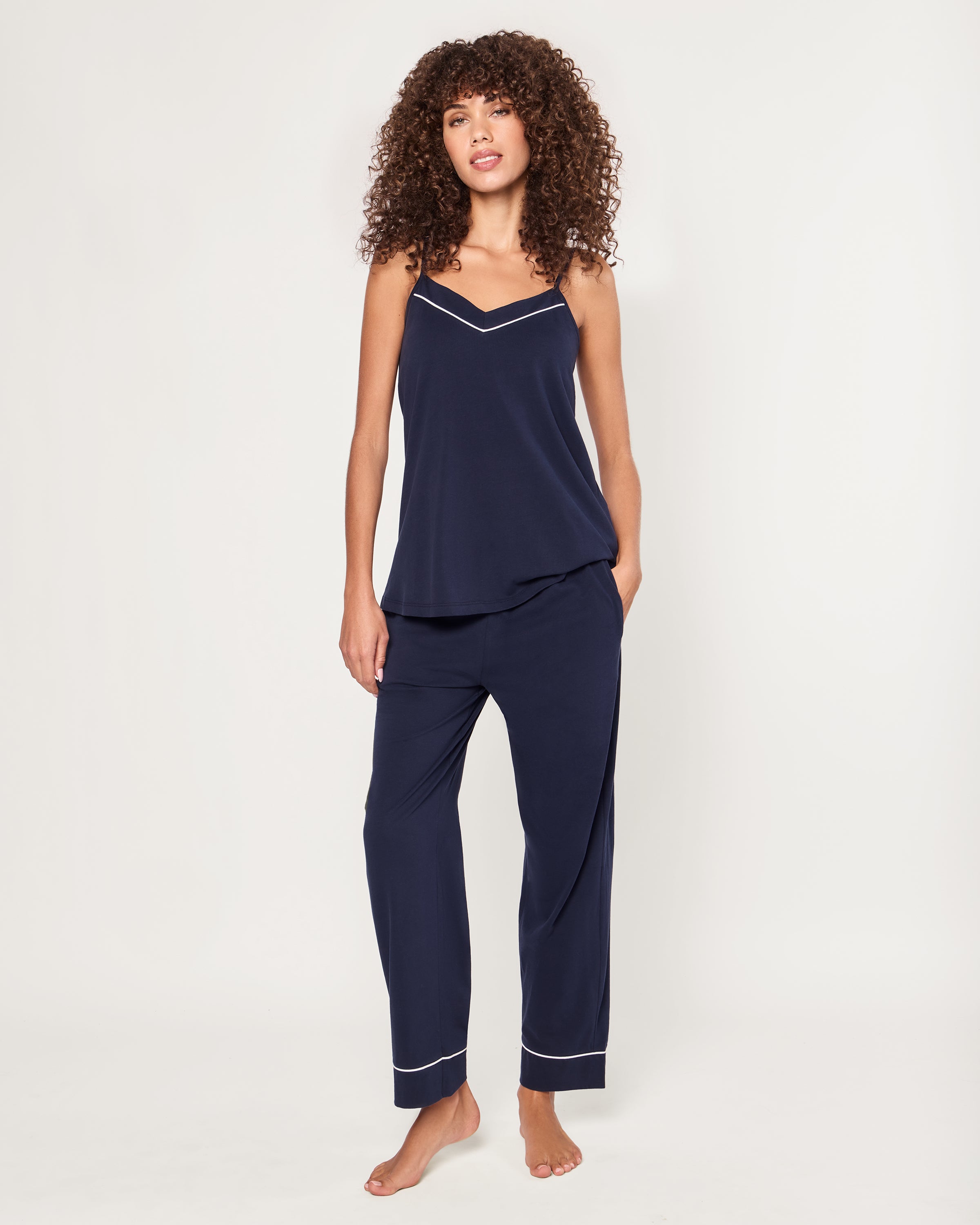 The Women's Pima Sylvie Pajama Set in Navy includes a sleeveless V-neck camisole with thin straps and matching long pants, both featuring white trim. The set is displayed flat on a white background.