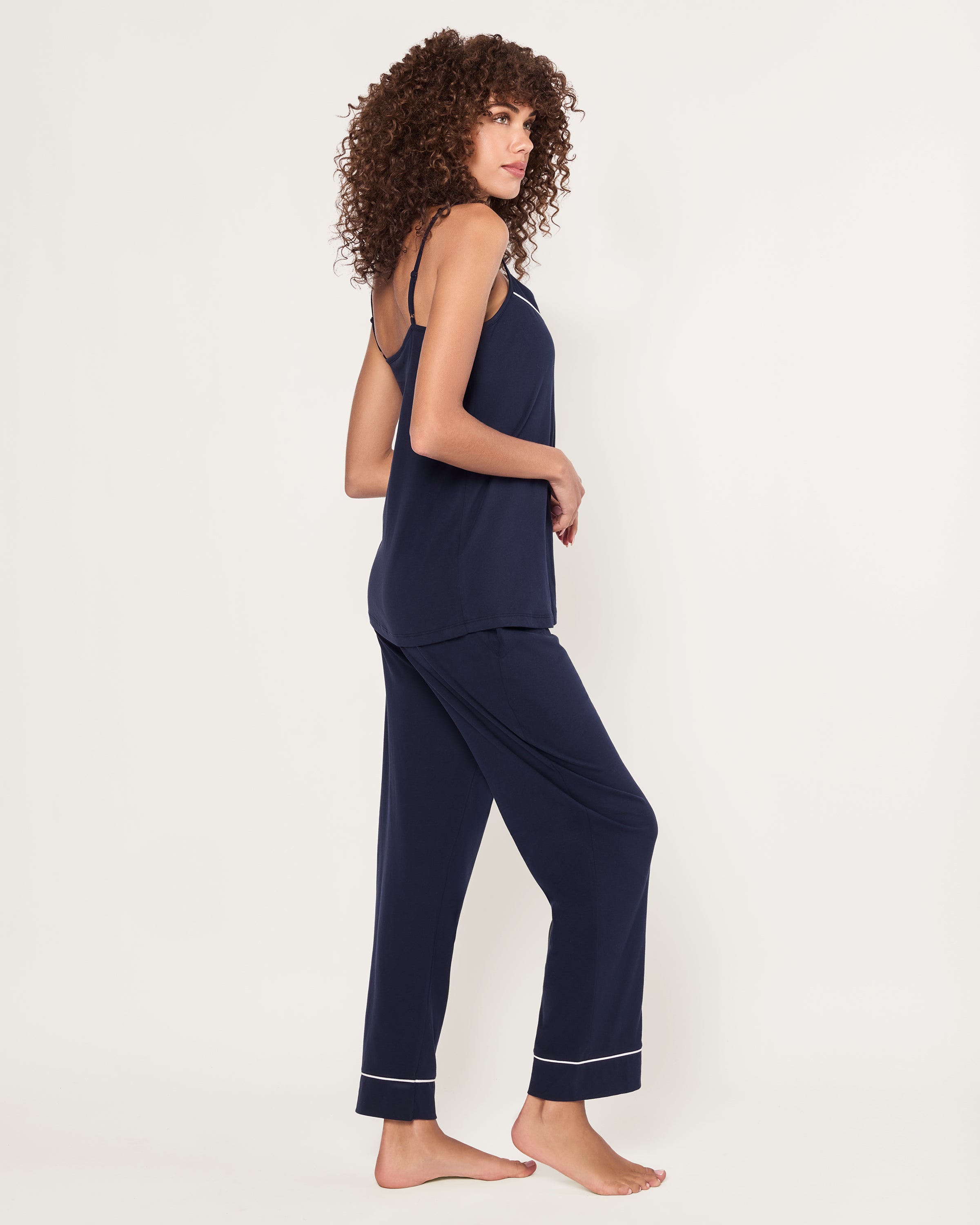 The Women's Pima Sylvie Pajama Set in Navy includes a sleeveless V-neck camisole with thin straps and matching long pants, both featuring white trim. The set is displayed flat on a white background.