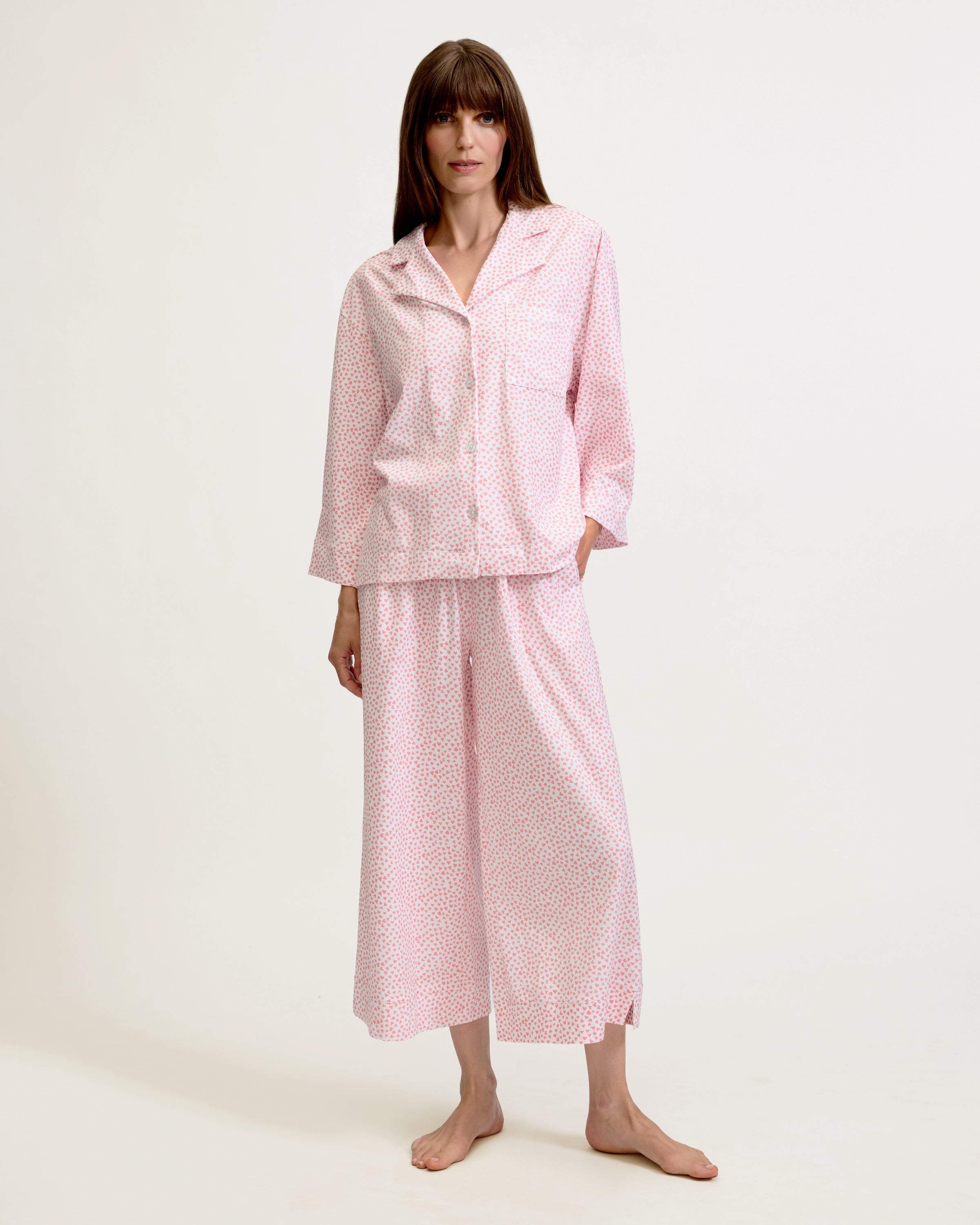 The Olivia Wide Leg Pima Pajama Set in Sweethearts features a light pink and white dotted design, with a collared long-sleeve button-up top and matching wide-leg drawstring pants.