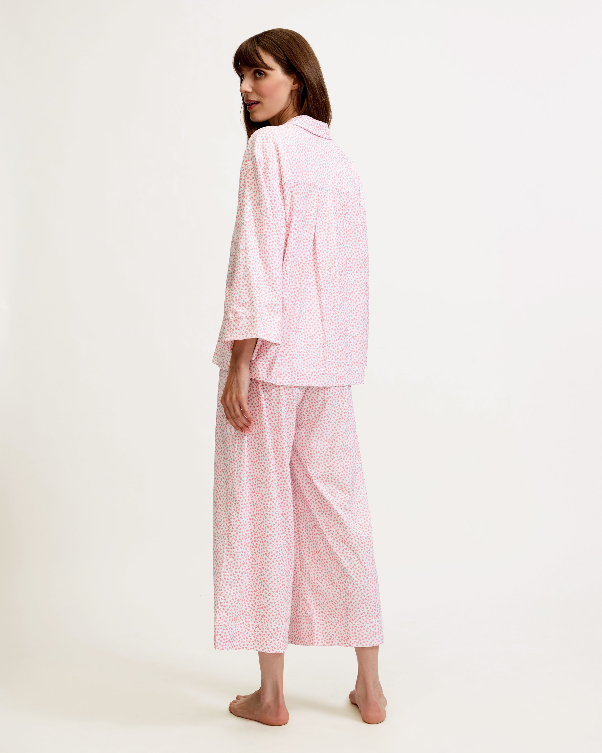 The Olivia Wide Leg Pima Pajama Set in Sweethearts features a light pink and white dotted design, with a collared long-sleeve button-up top and matching wide-leg drawstring pants.